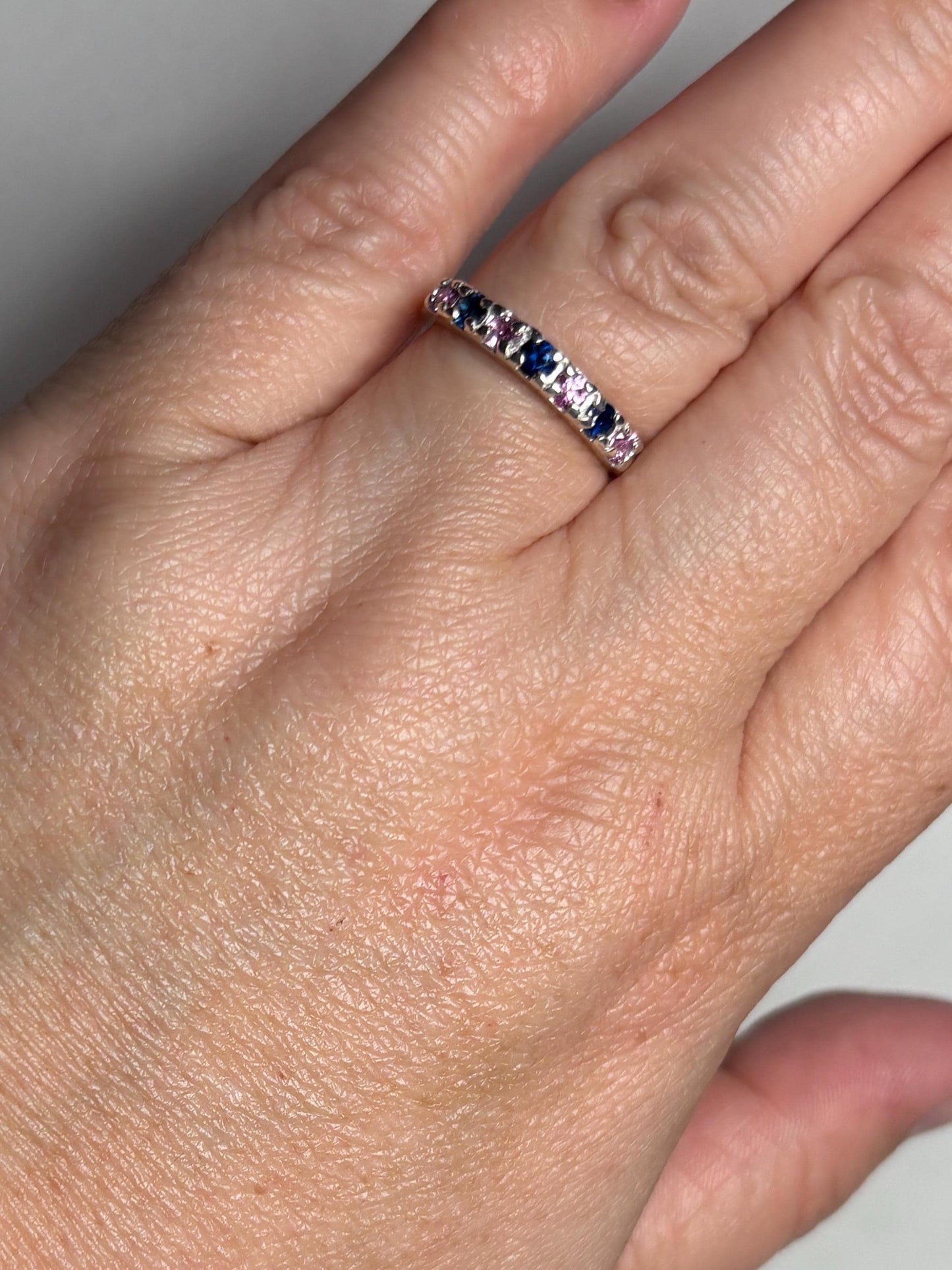 Sterling silver band ring with alternating blue and pink sapphires.