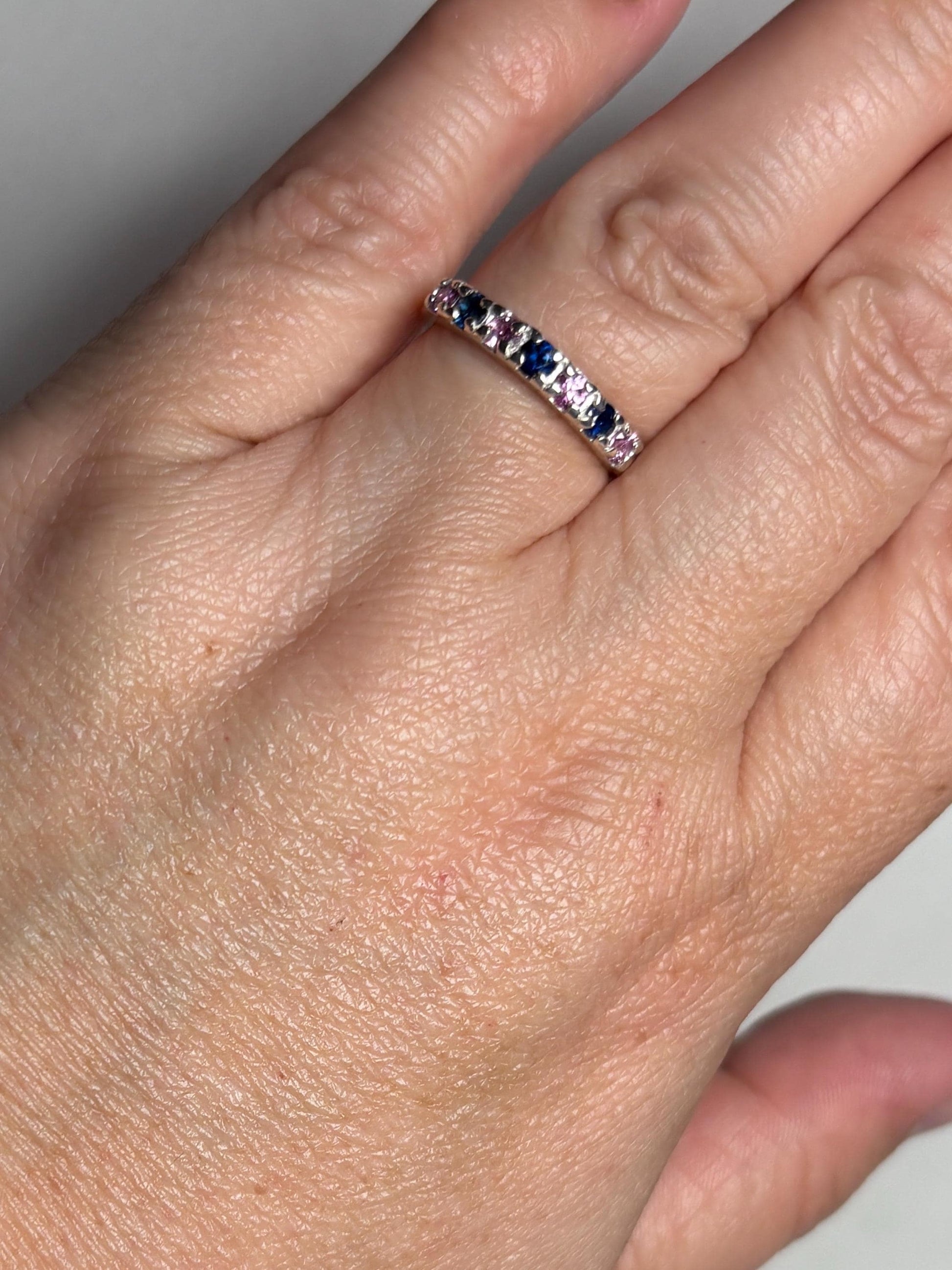 Sterling silver band ring with alternating blue and pink sapphires.