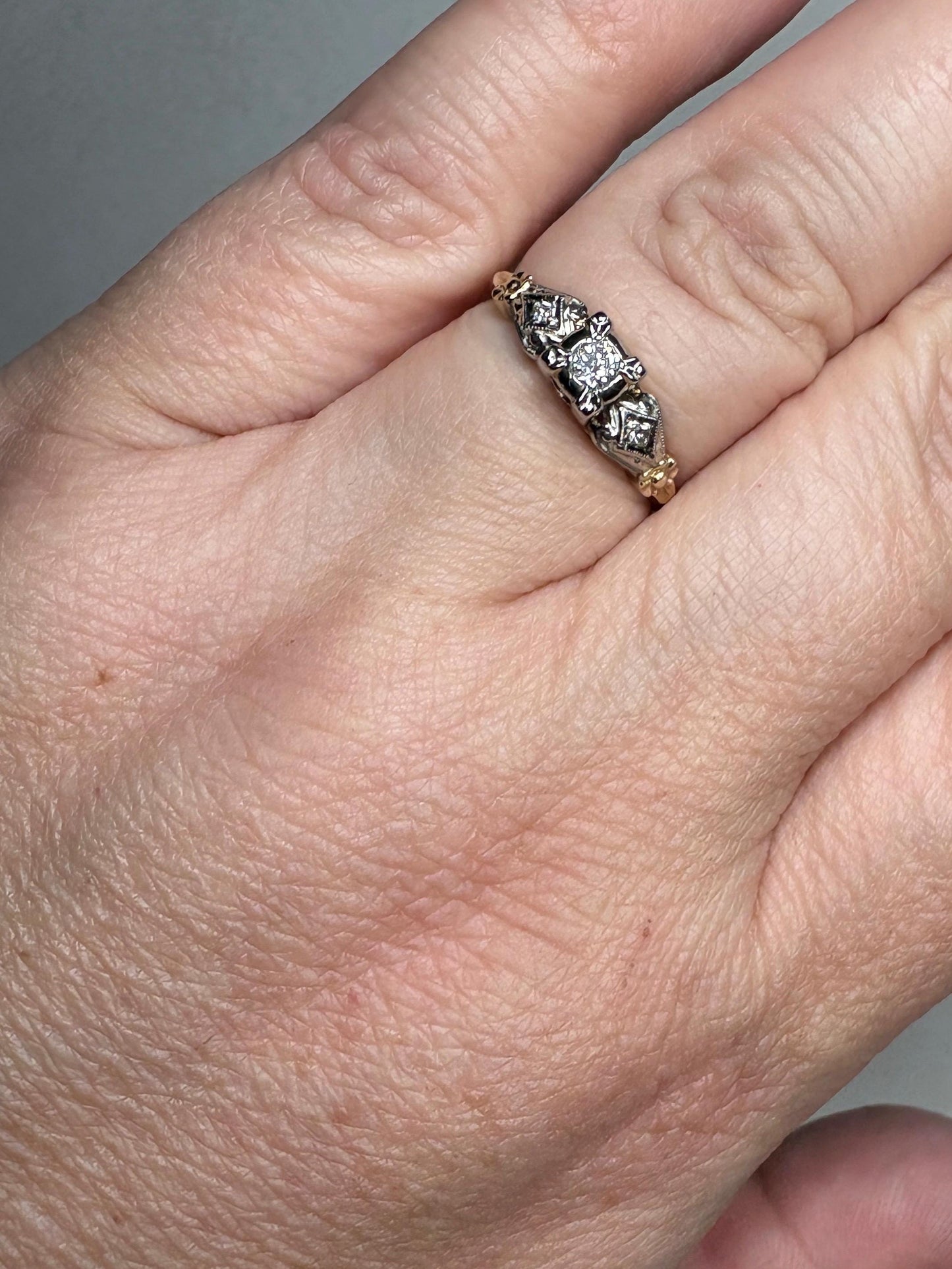 Vintage two-tone 14k gold ring with a central diamond and two smaller diamonds.