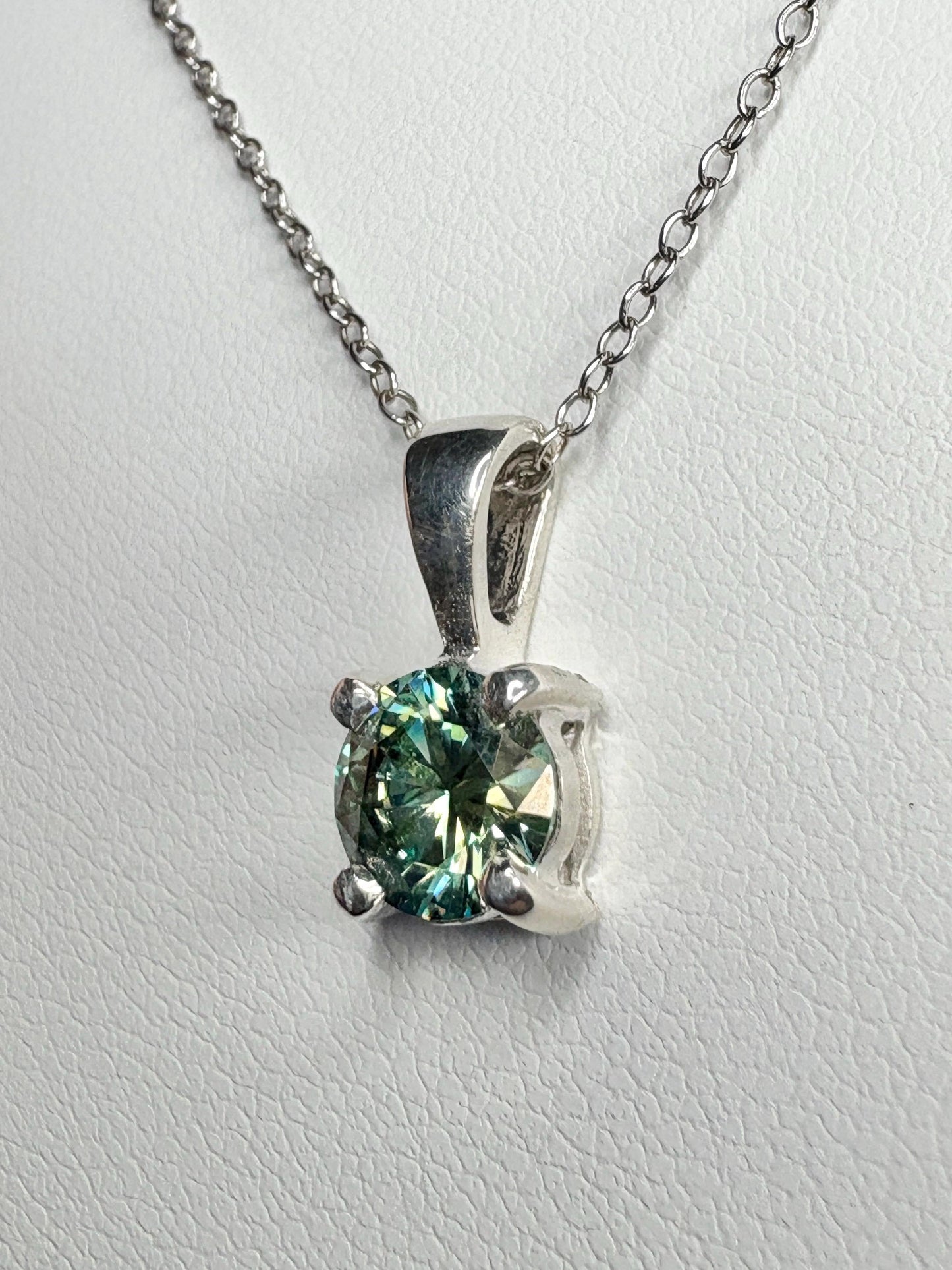 Sterling silver pendant necklace with a teal-green moissanite solitaire.