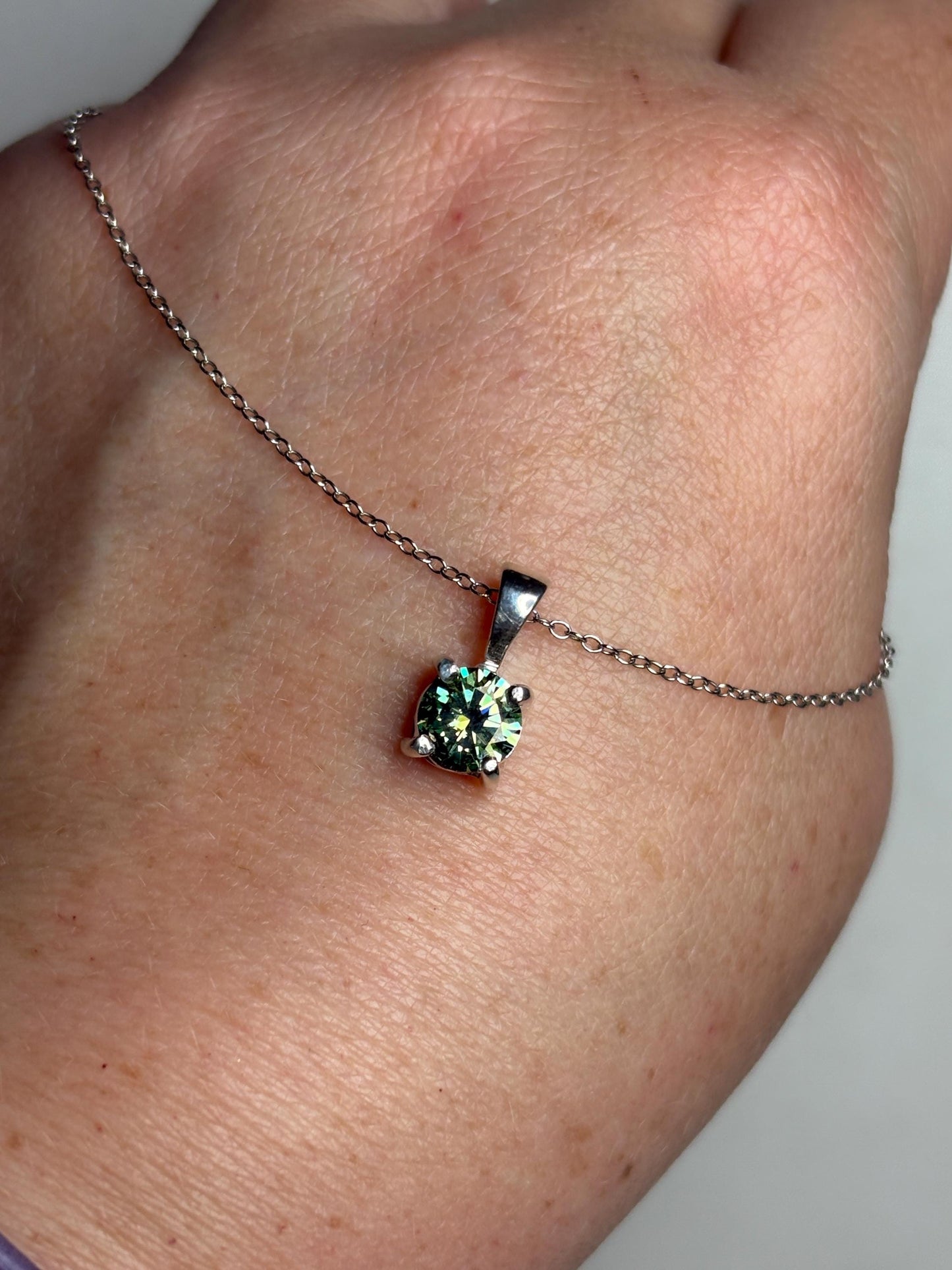 Teal-green moissanite solitaire pendant necklace on an 18-inch sterling silver cable chain.