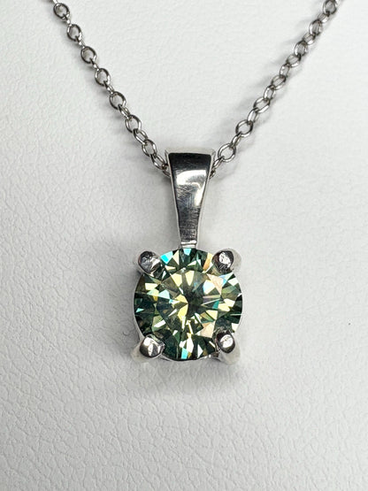 Sterling silver pendant necklace with a teal-green moissanite gemstone.