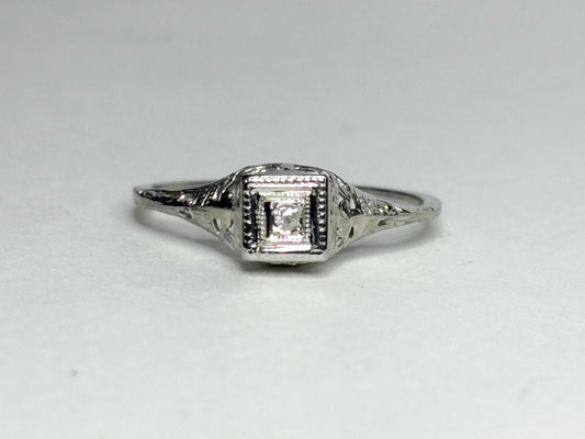 Art Deco 18k gold ring with a diamond chip and filigree details.