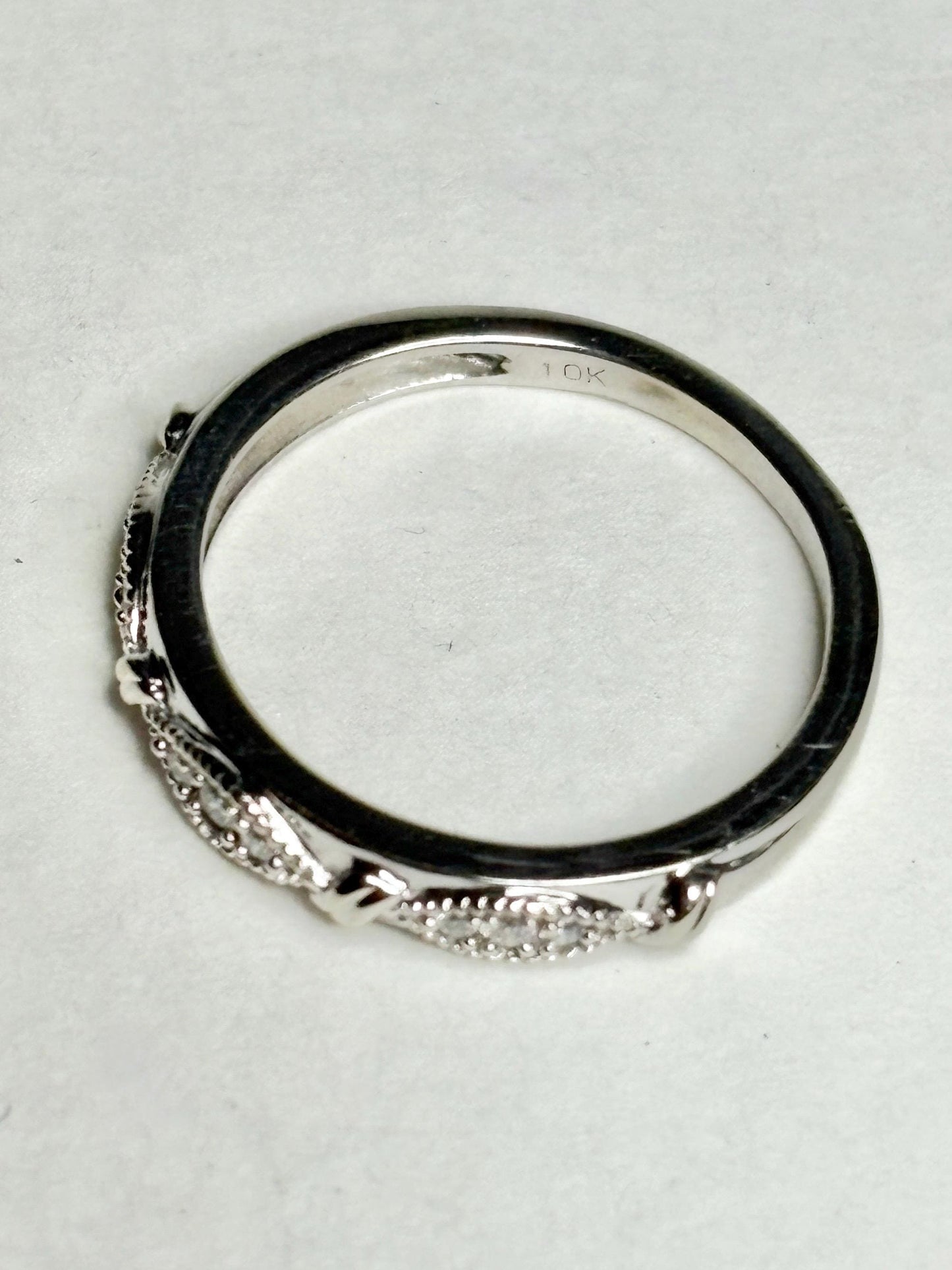 A 10k white gold band ring with milgrain detailing and small diamonds.