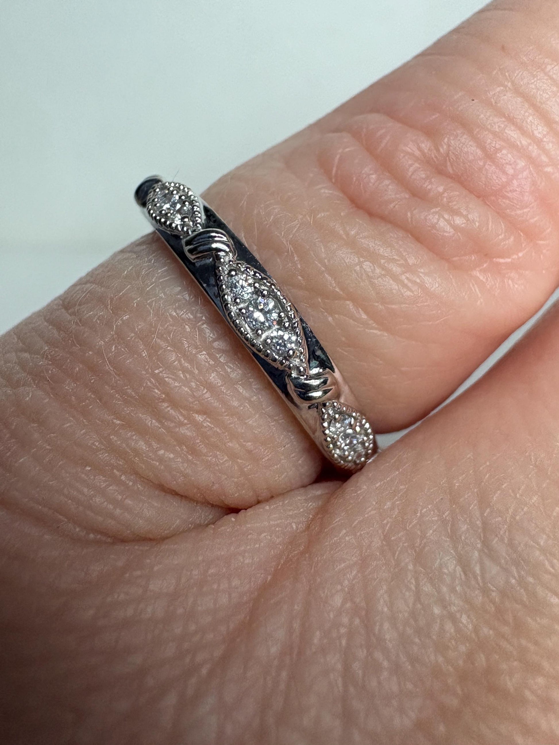 A stackable 10k white gold ring with diamonds and milgrain detail.