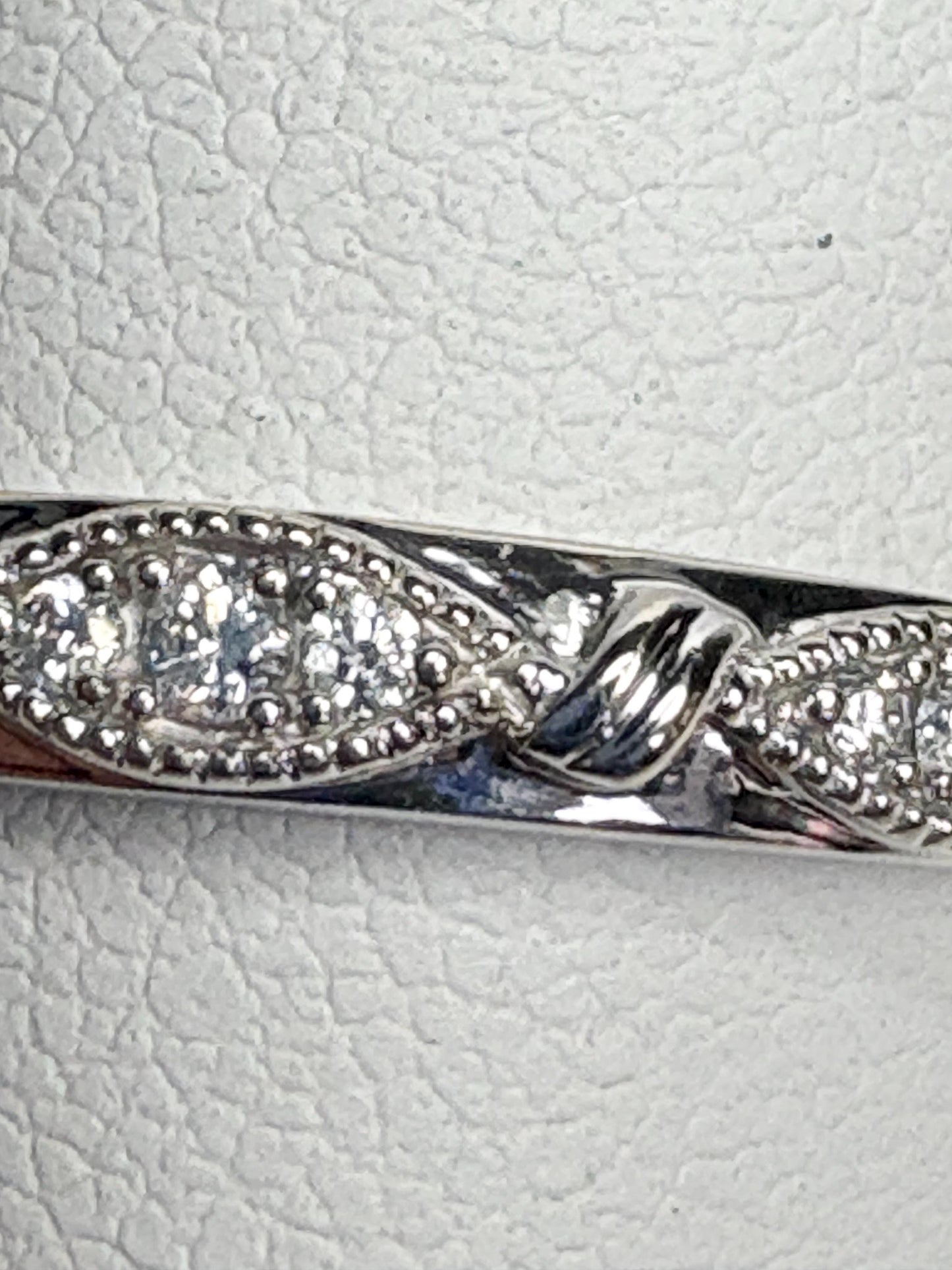 A 10k white gold band ring with milgrain detail and small diamonds.