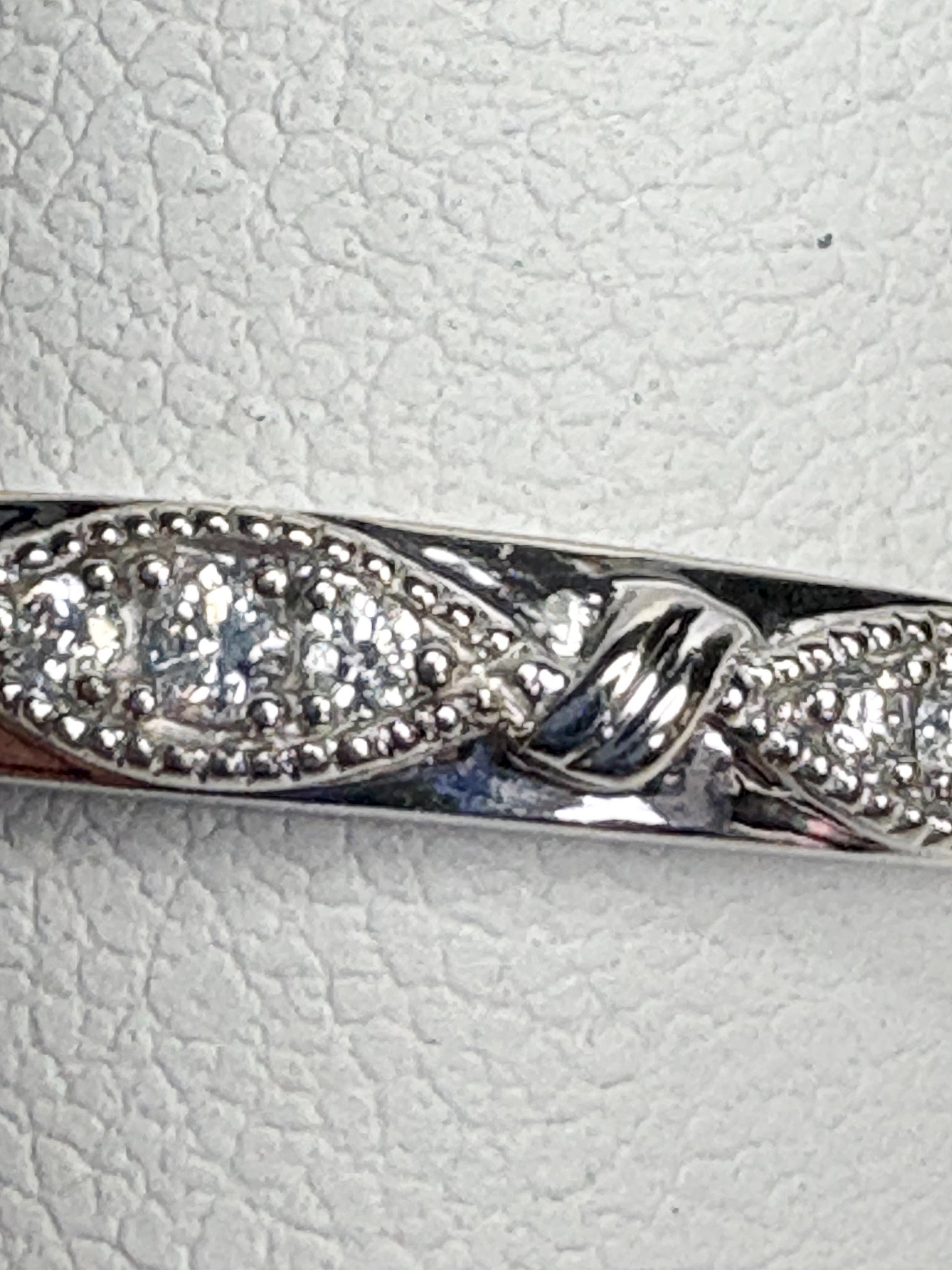 A 10k white gold band ring with milgrain detail and small diamonds.