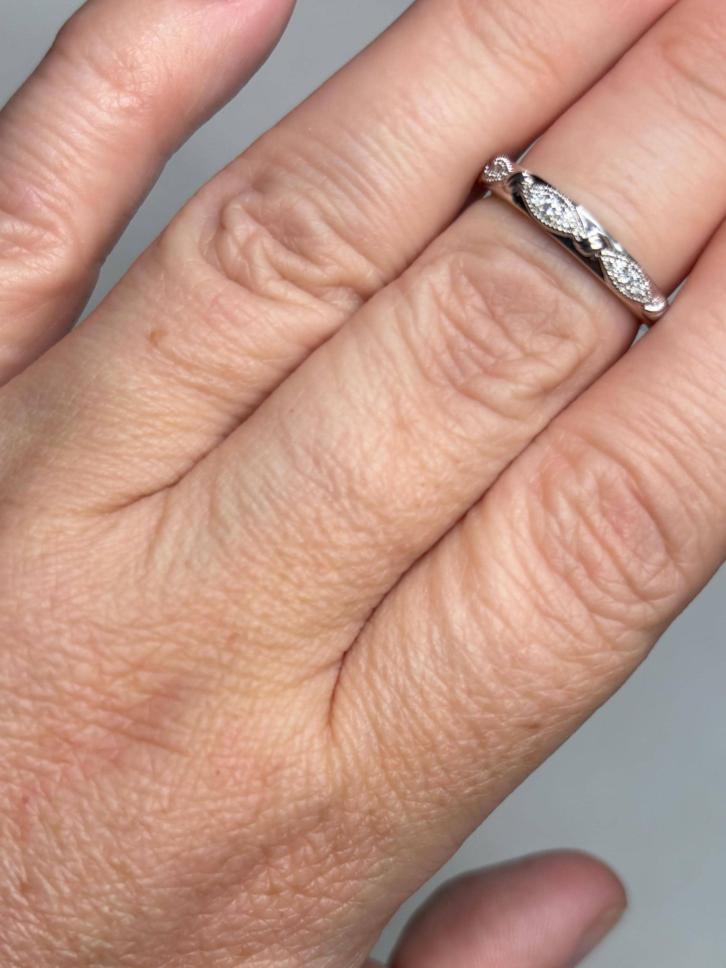 A stackable 10k white gold band ring with milgrain detailing and small diamonds.