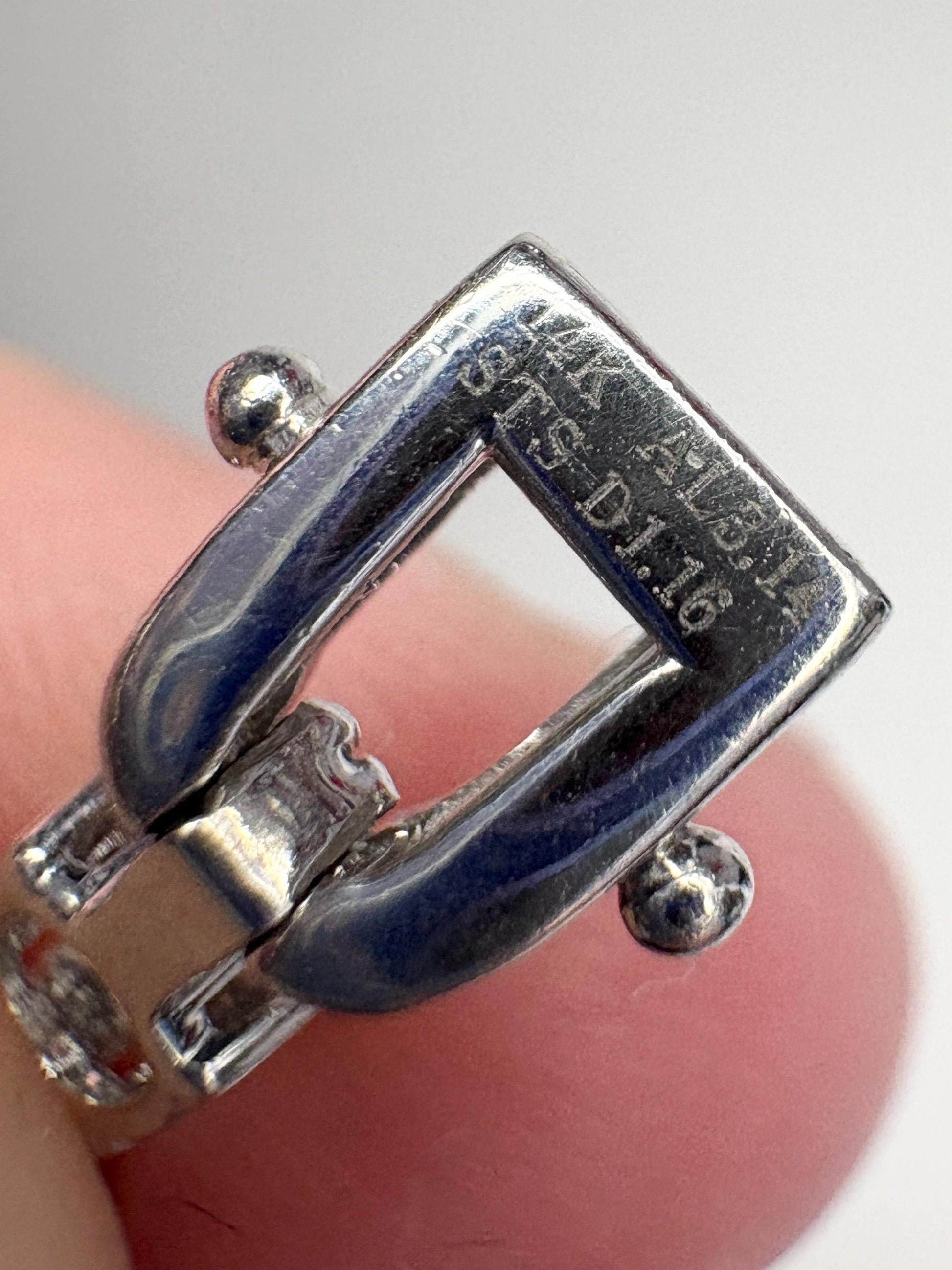 Close-up of a 14k white gold bracelet clasp with inscription.