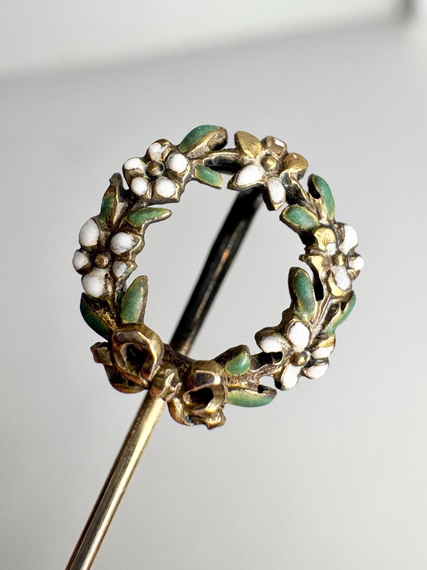 14k gold stick pin with an enameled floral wreath.