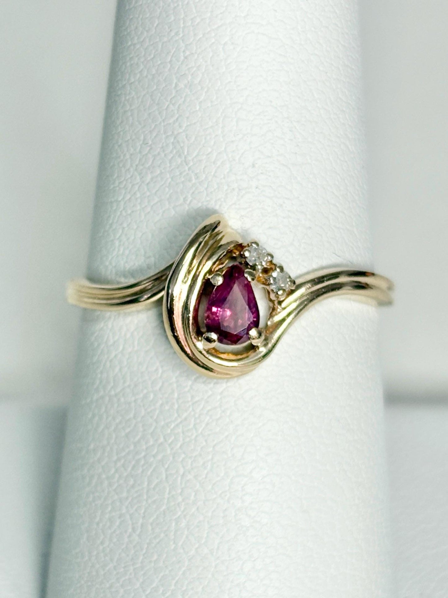 10k gold ring with a pear-shaped ruby and diamond accents.