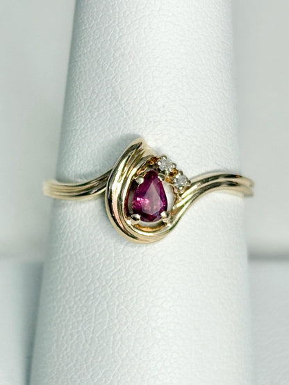 10k gold ring with a pear-shaped ruby and diamond accents.