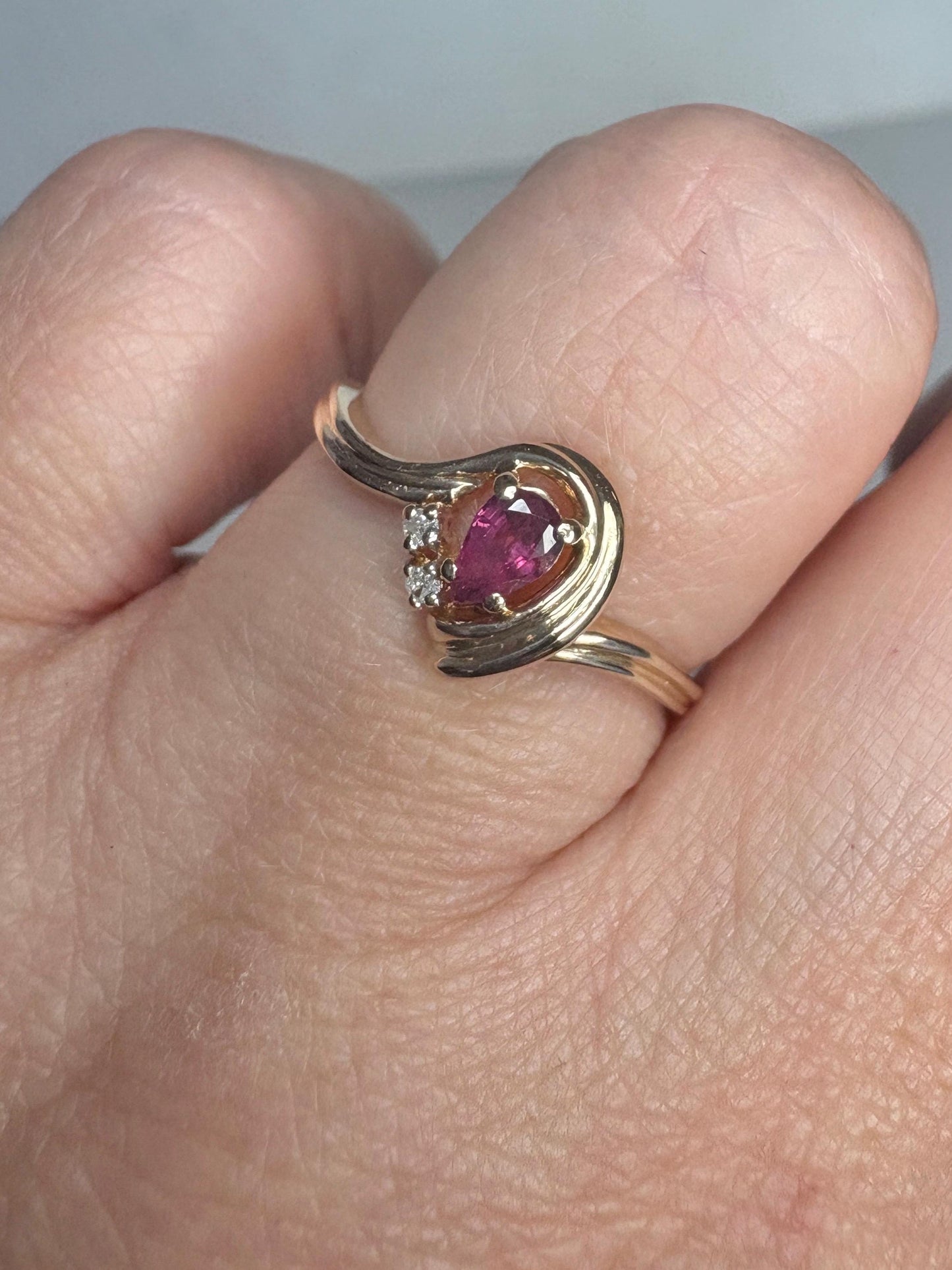 10k gold ring with a pear-shaped ruby and diamond accents.