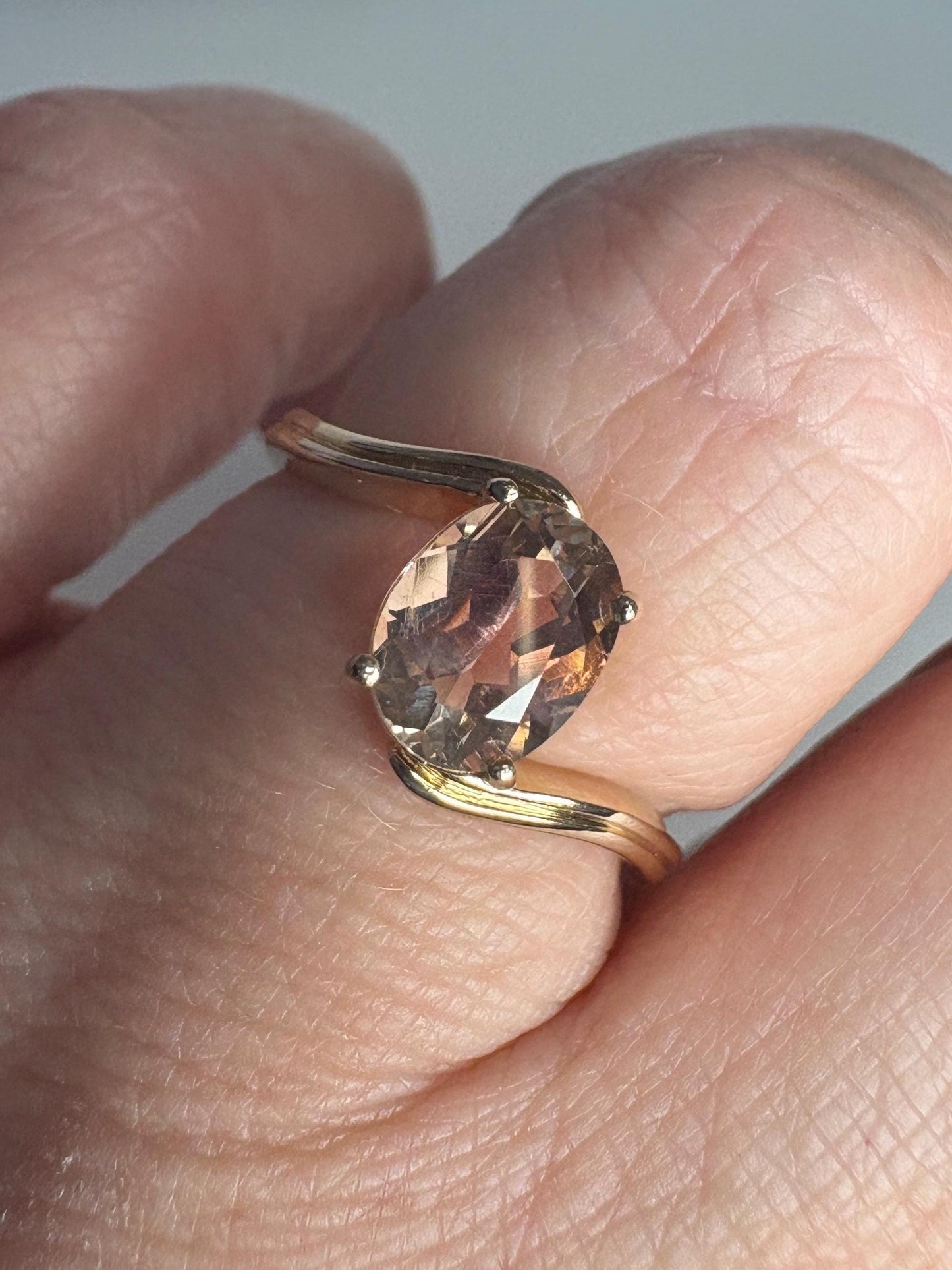 A 14k gold bypass ring with a light peach oval Oregon sunstone.