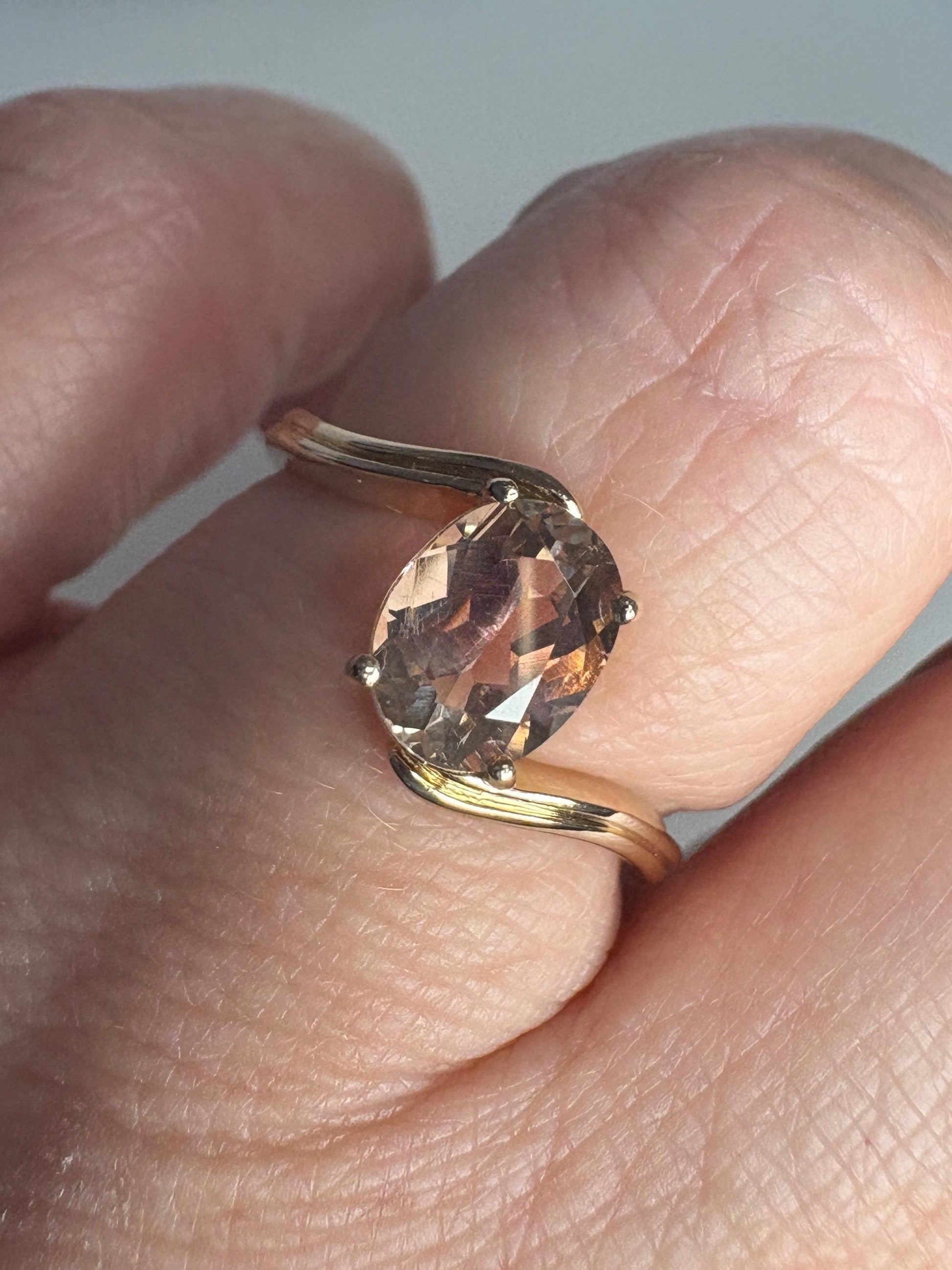A 14k gold bypass ring with a light peach oval Oregon sunstone.