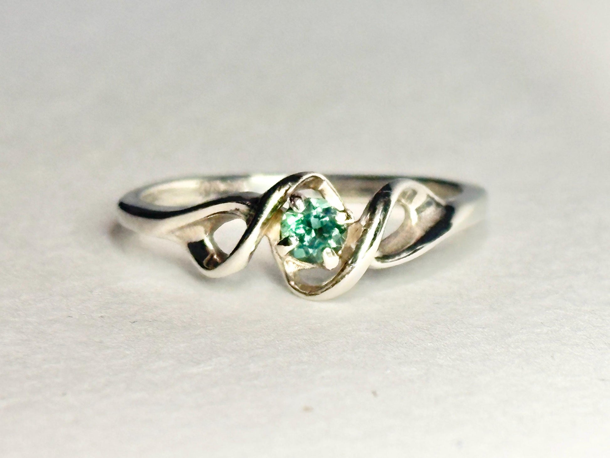 A 10k white gold band ring with a natural blue-green tourmaline.