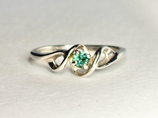 A 10k white gold band ring with a natural blue-green tourmaline.