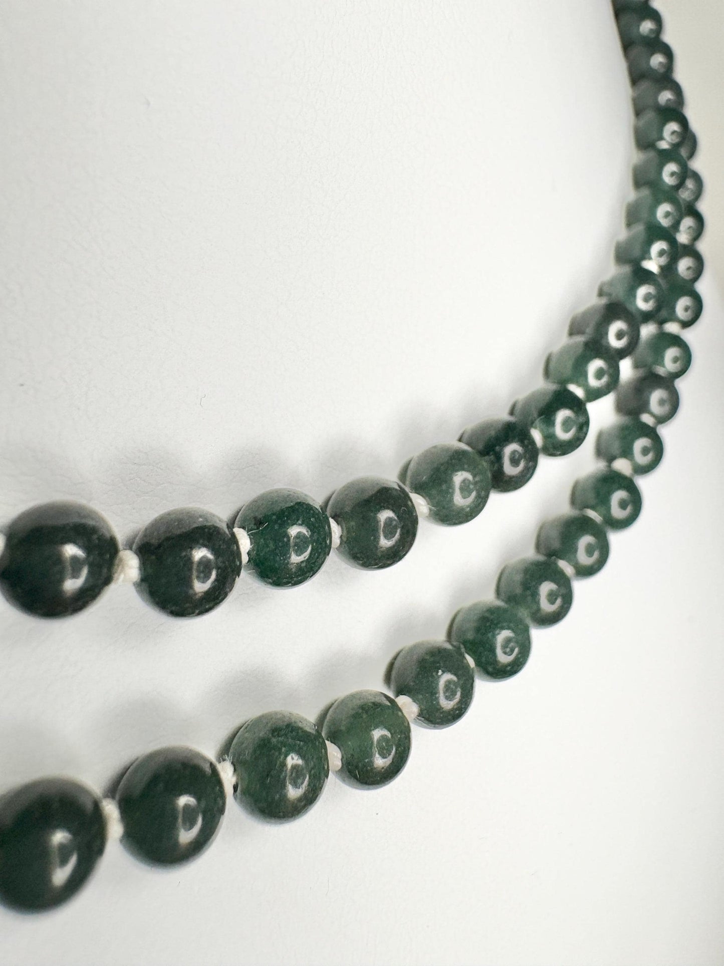 Teal jadeite jade beads on a white silk cord with a sterling silver clasp.