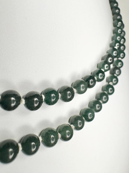 Teal jadeite jade beads on a white silk cord with a sterling silver clasp.