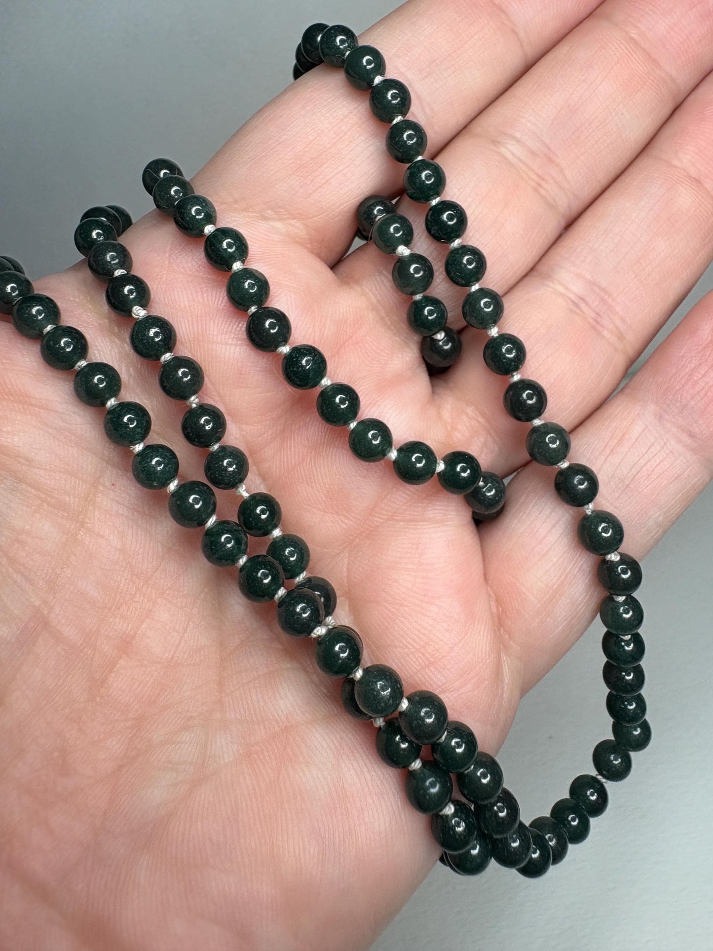 A long, teal jadeite jade beaded necklace with a sterling silver clasp.