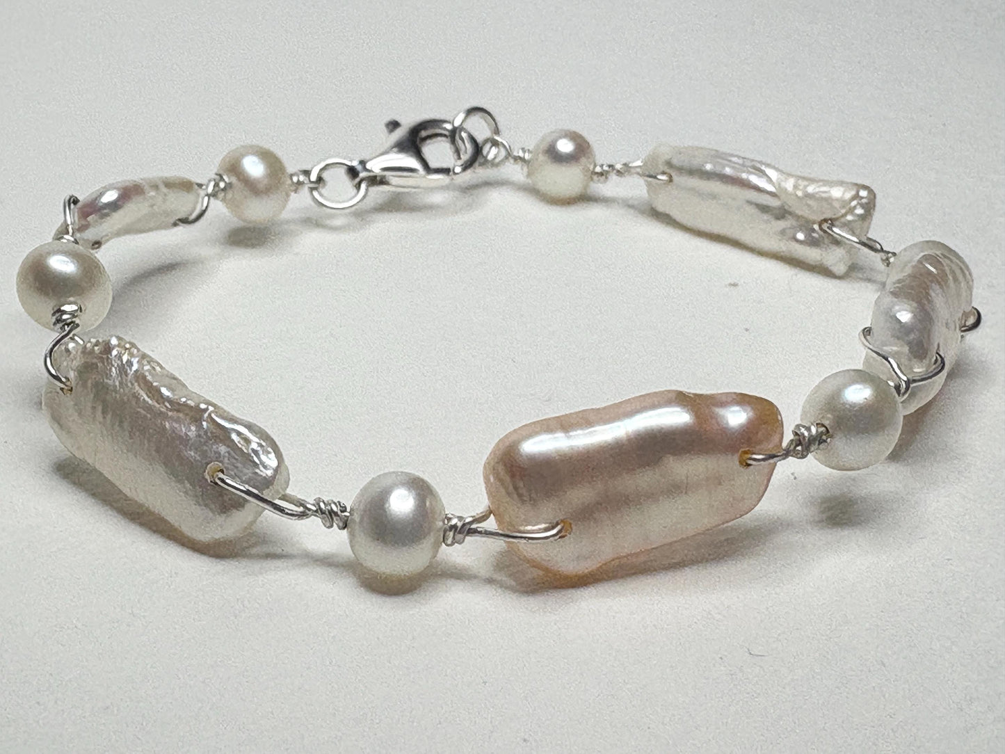 Sterling silver bracelet with white and peach biwa freshwater pearls.