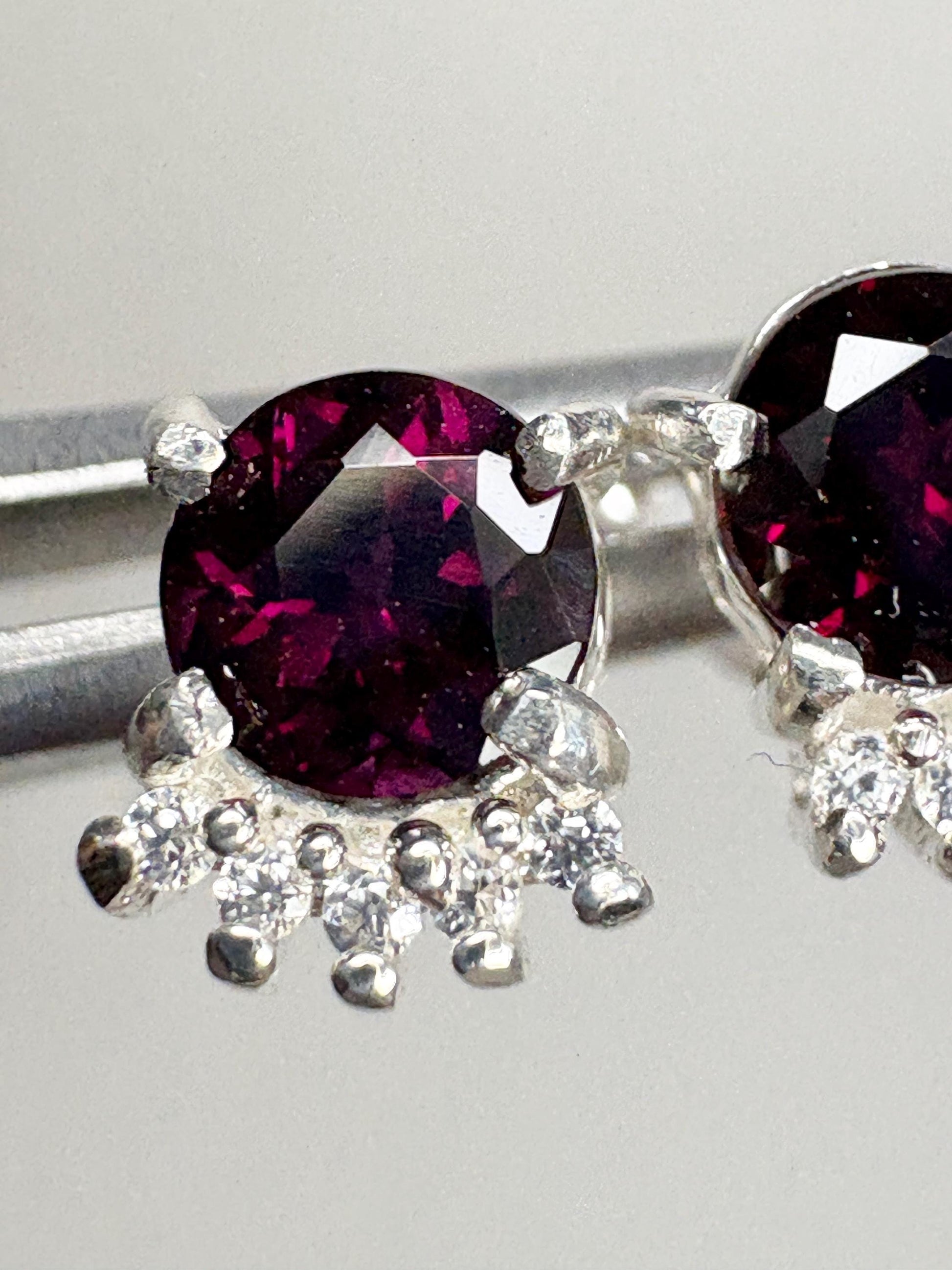 Sterling silver stud earrings featuring oval Arizona anthill garnets and round white zircons.