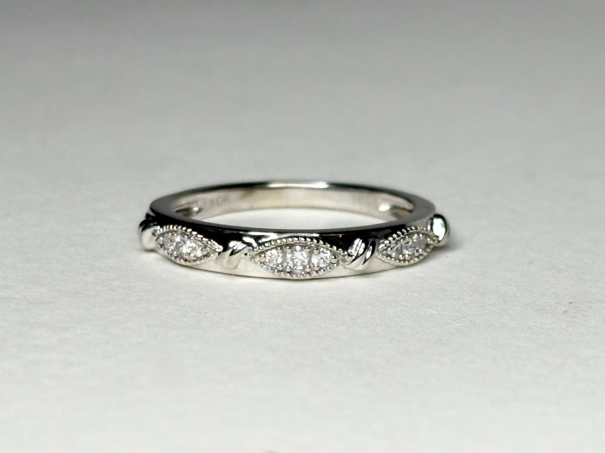A 10k white gold band ring with diamonds and milgrain detailing.