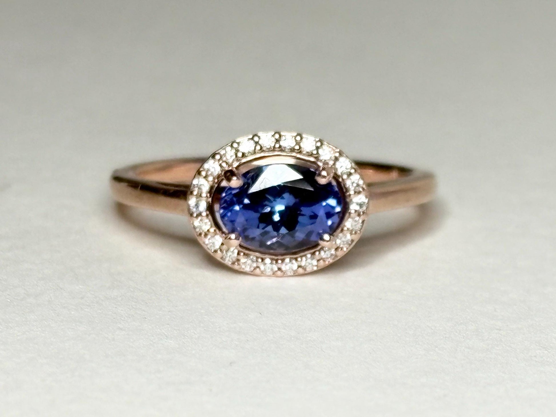 Oval tanzanite and diamond halo ring in 14k rose gold.