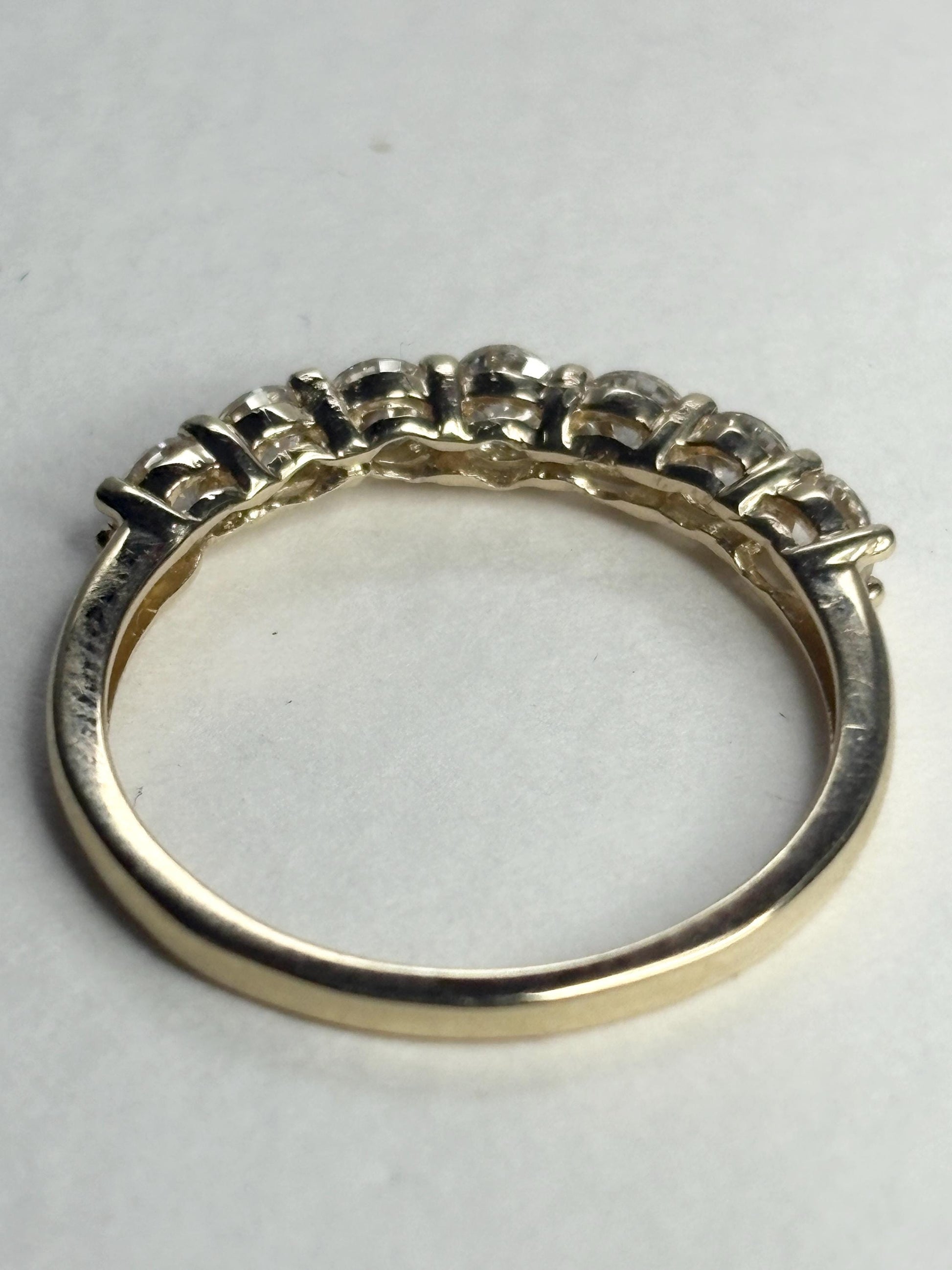 Solid 10k yellow gold band ring with seven moissanite stones.