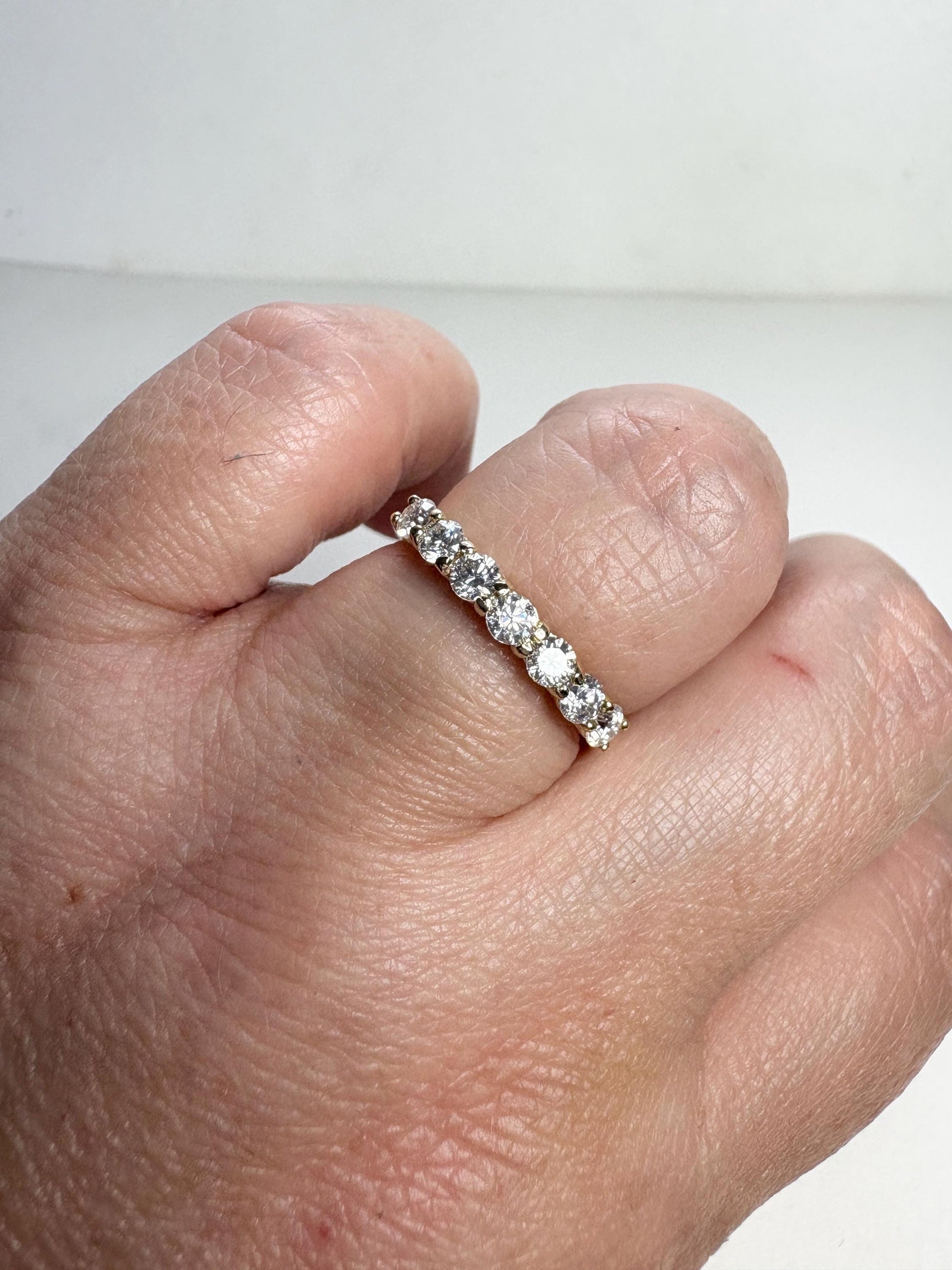 A 10k gold band ring with seven moissanite stones.