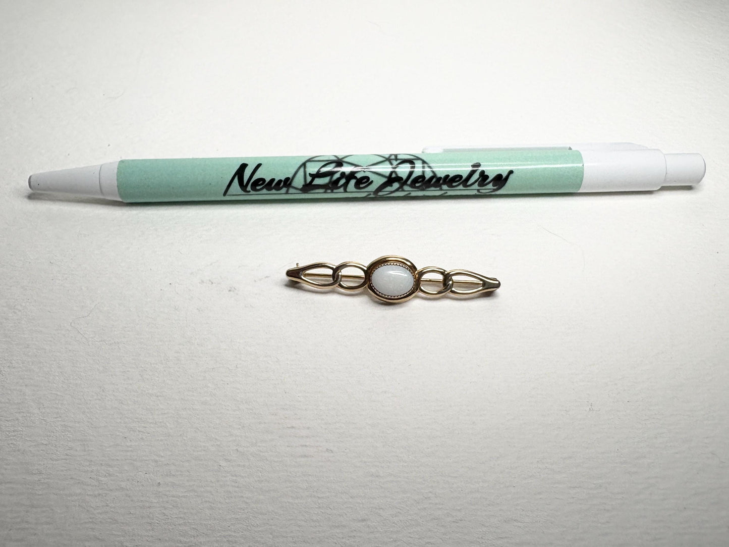 Solid 14k gold bar brooch with an oval white opal.