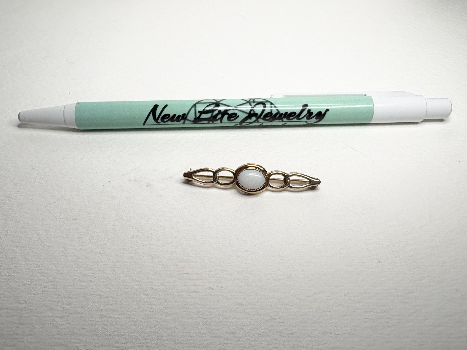 Solid 14k gold bar brooch with an oval white opal.