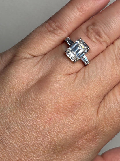 Sterling silver ring with a large emerald-cut cubic zirconia and two baguette side stones.