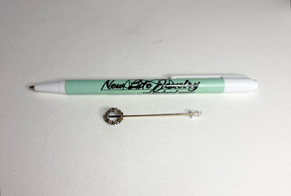 A 14k gold stick pin featuring a floral wreath with enameled leaves and flowers.