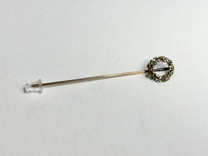 A 14k gold stick pin with an enameled floral wreath.