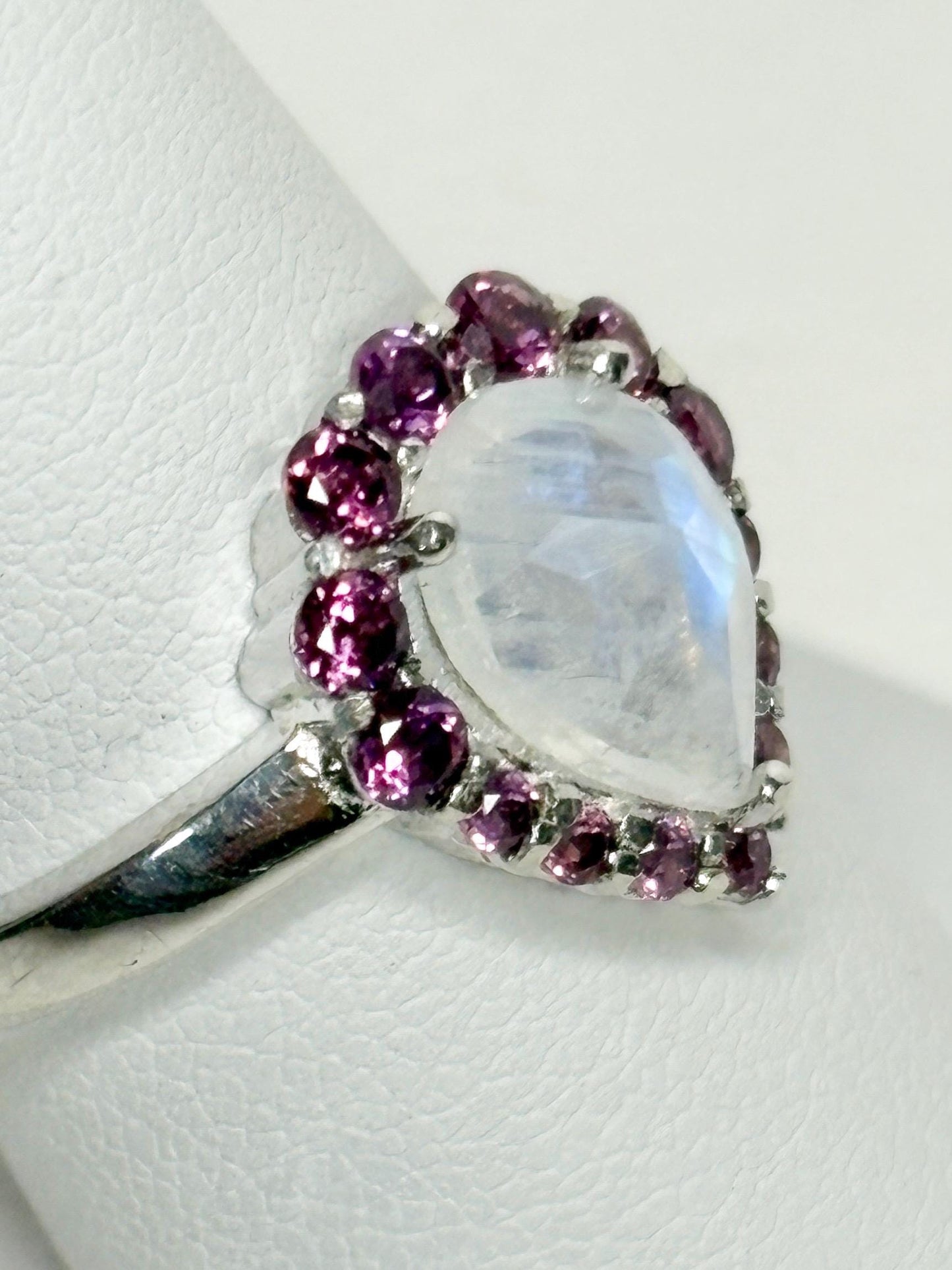 Sterling silver ring with a pear-shaped rainbow moonstone surrounded by rhodolite garnets.