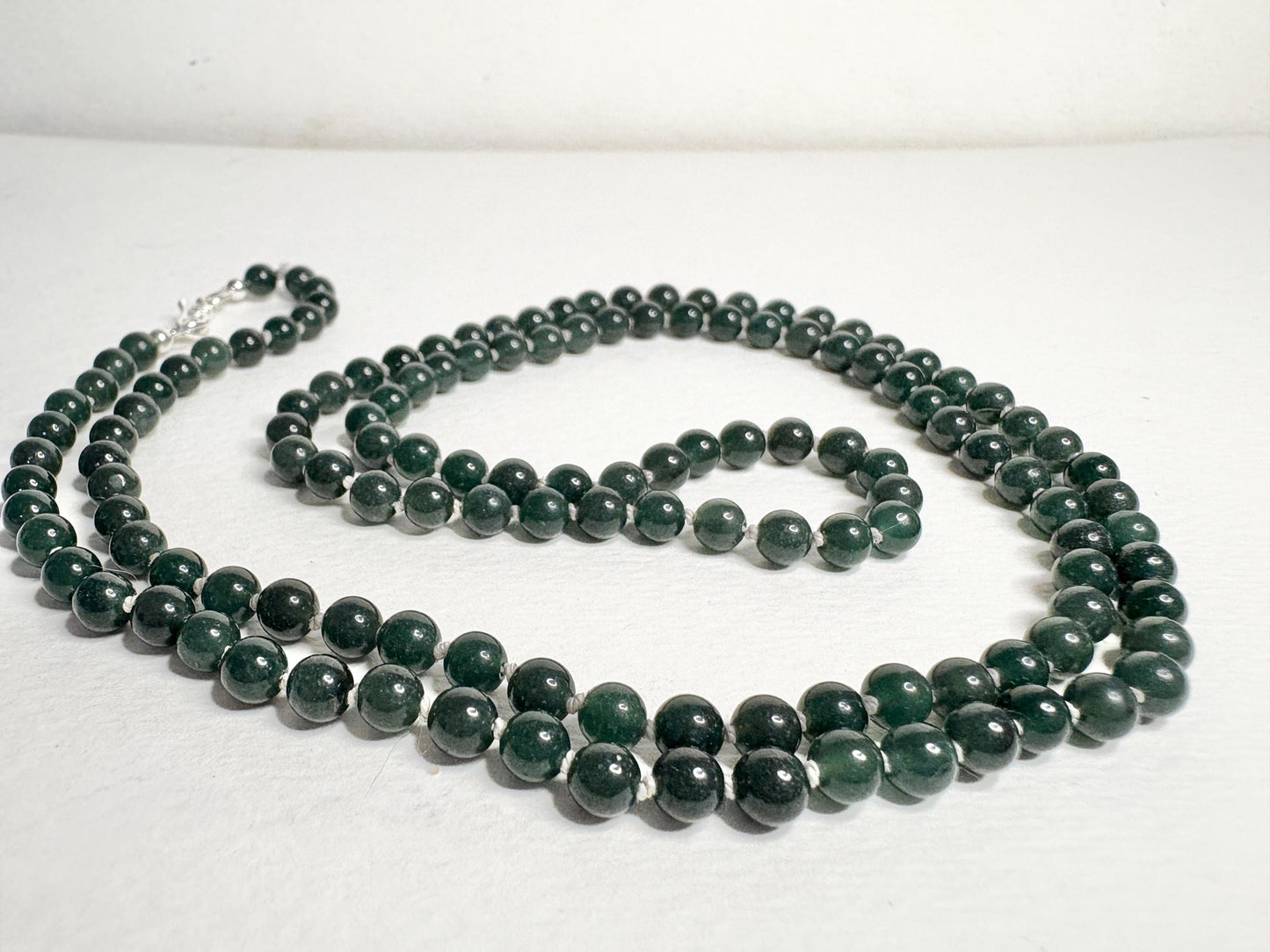 A long teal jadeite jade beaded necklace with a sterling silver clasp.