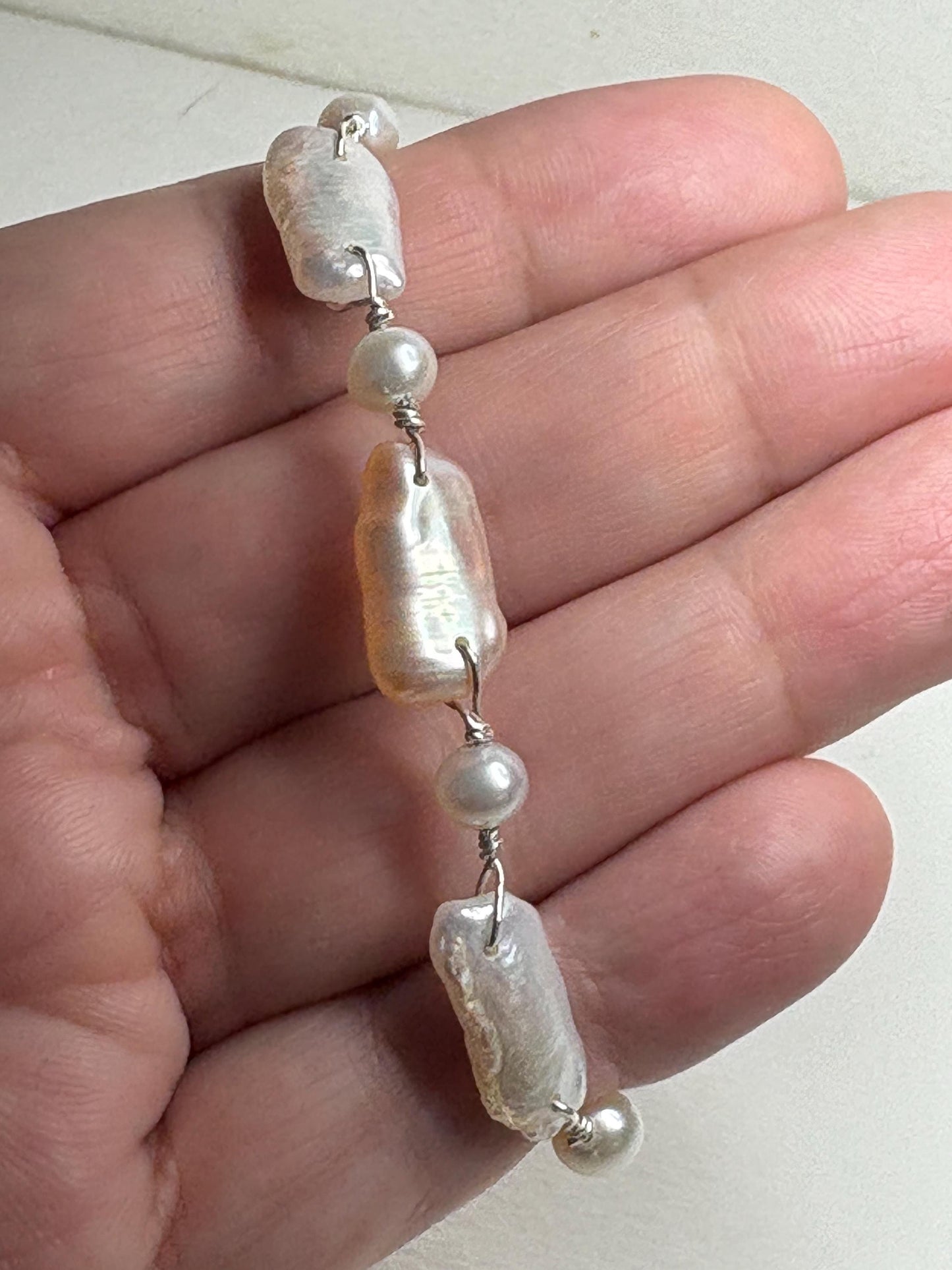 Sterling silver bracelet with irregular white and peach freshwater pearls.