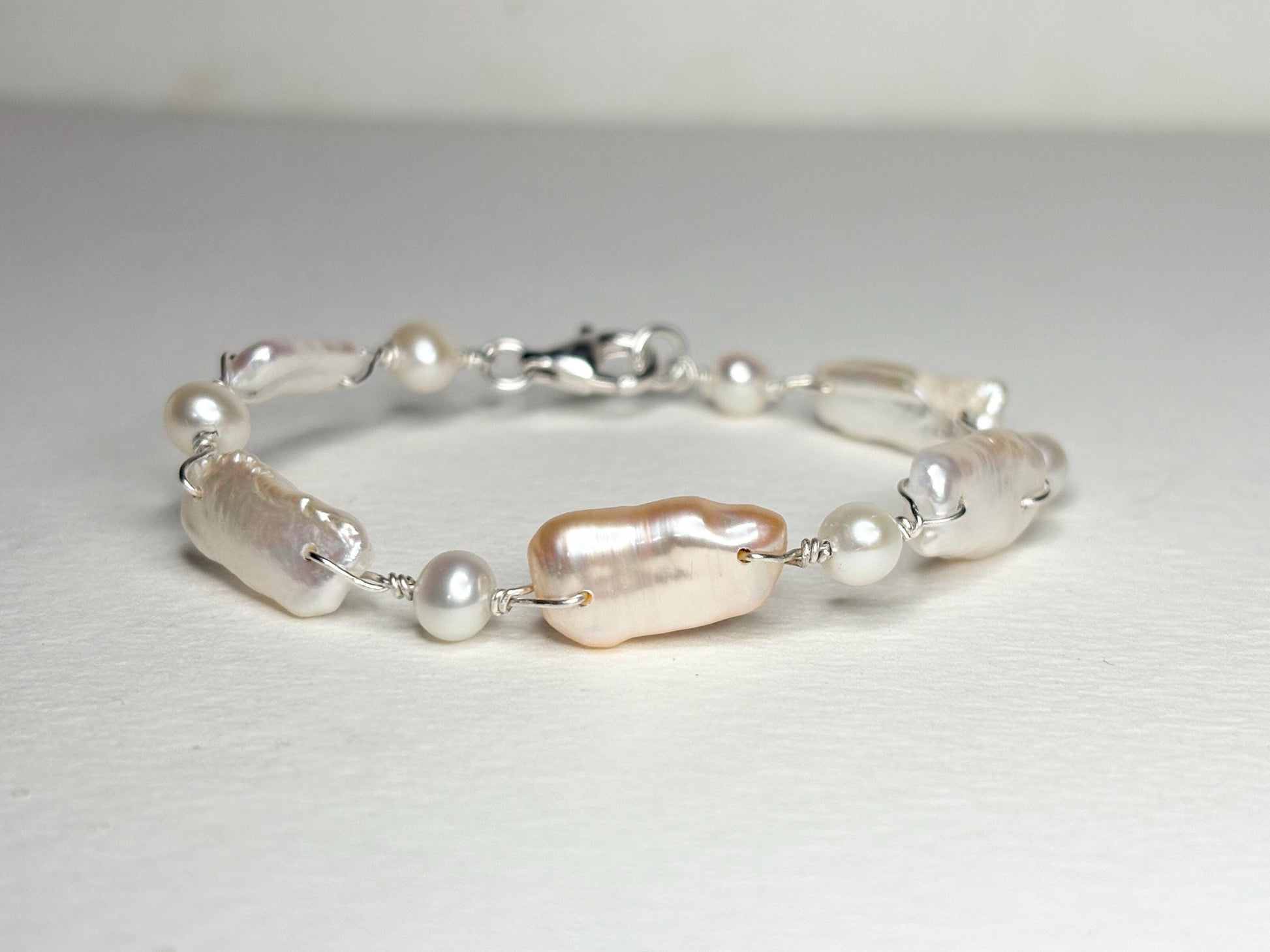 Sterling silver bracelet with irregular white and peach freshwater pearls.