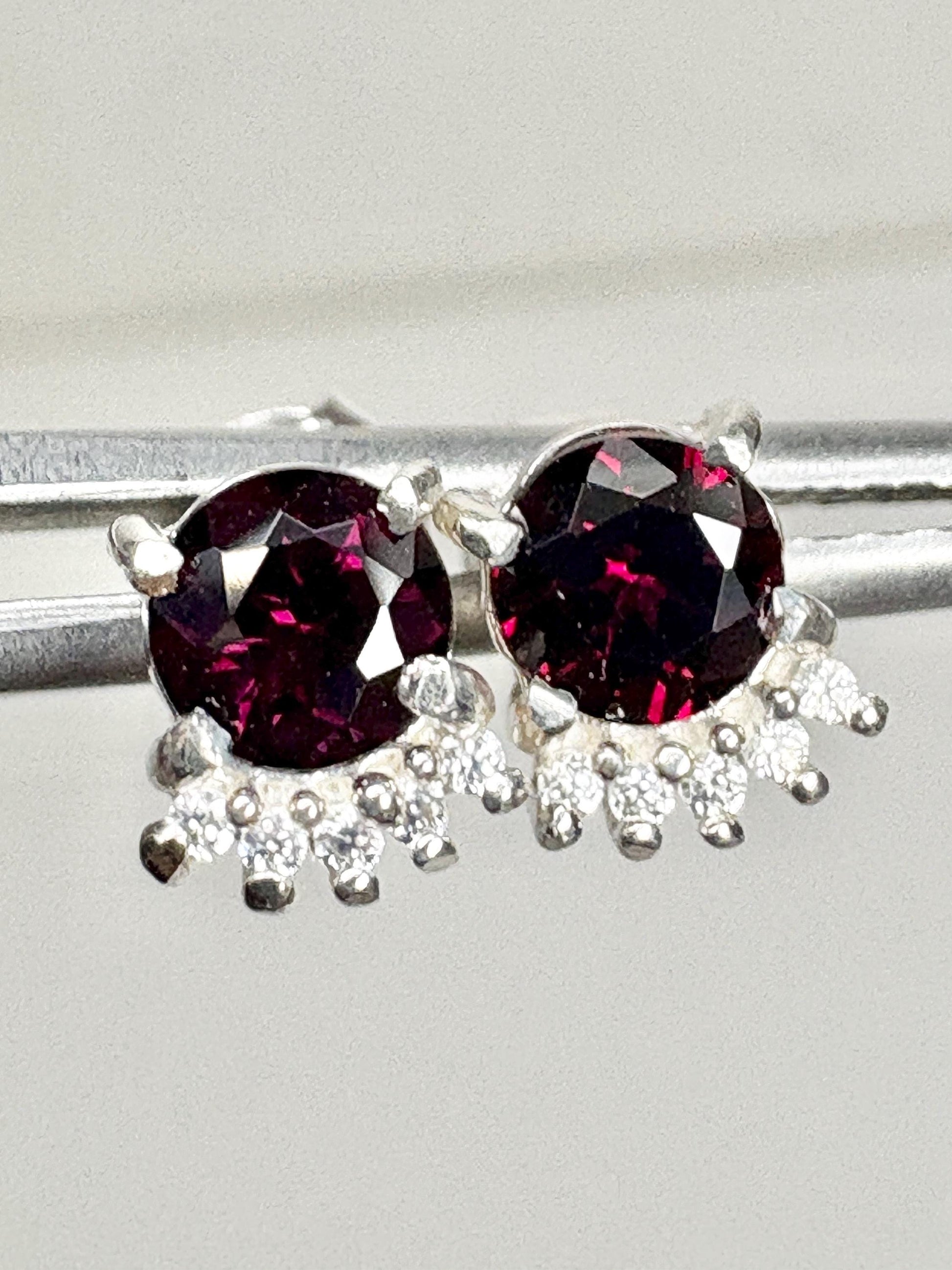 Sterling silver stud earrings with round garnets and small white zircons.