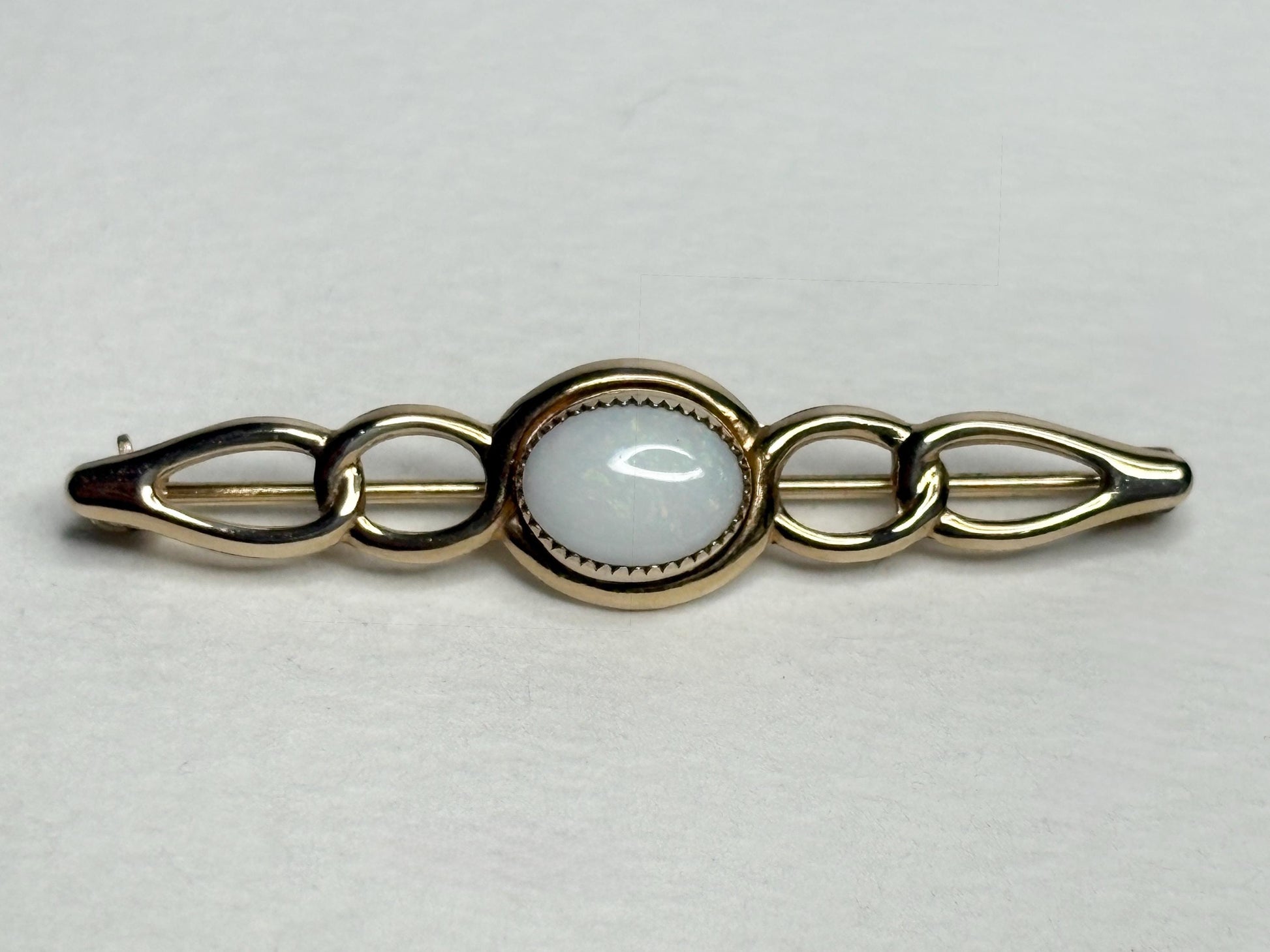 14k gold bar brooch with a white opal center.