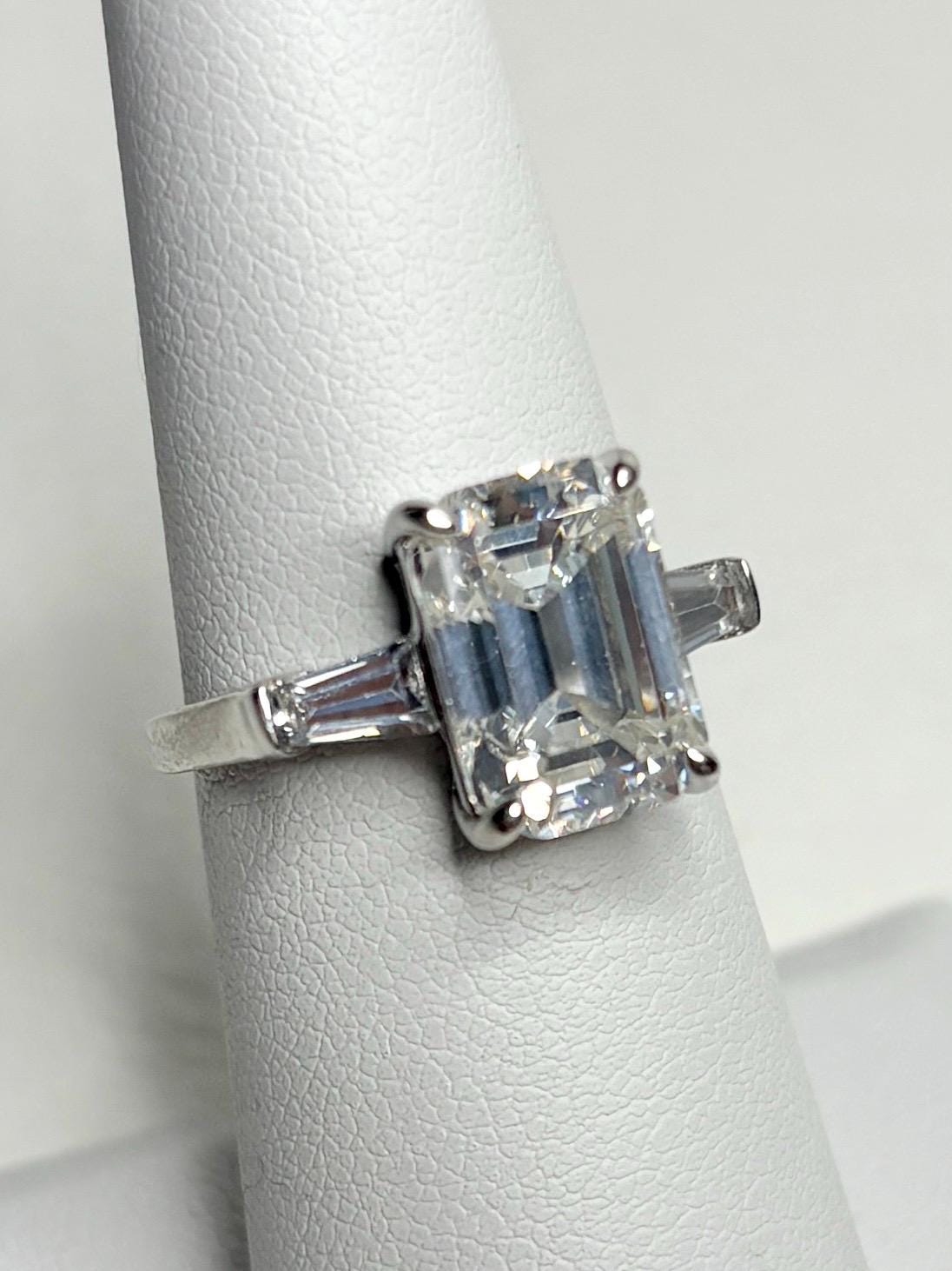 Sterling silver ring with a large emerald-cut cubic zirconia and two baguette side stones.