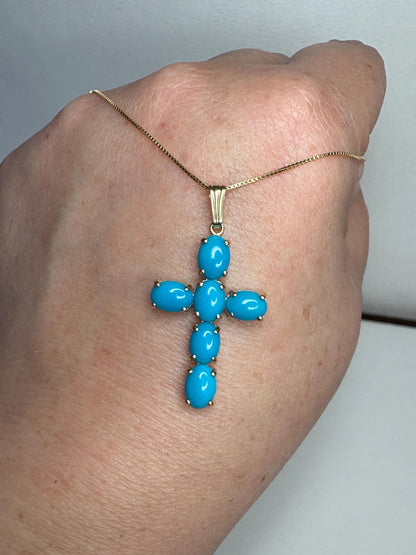 A 14k gold cross pendant necklace with six oval Sleeping Beauty turquoise stones.