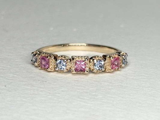 A 9k gold band ring with alternating pink princess cut and light violetish-blue round sapphires.