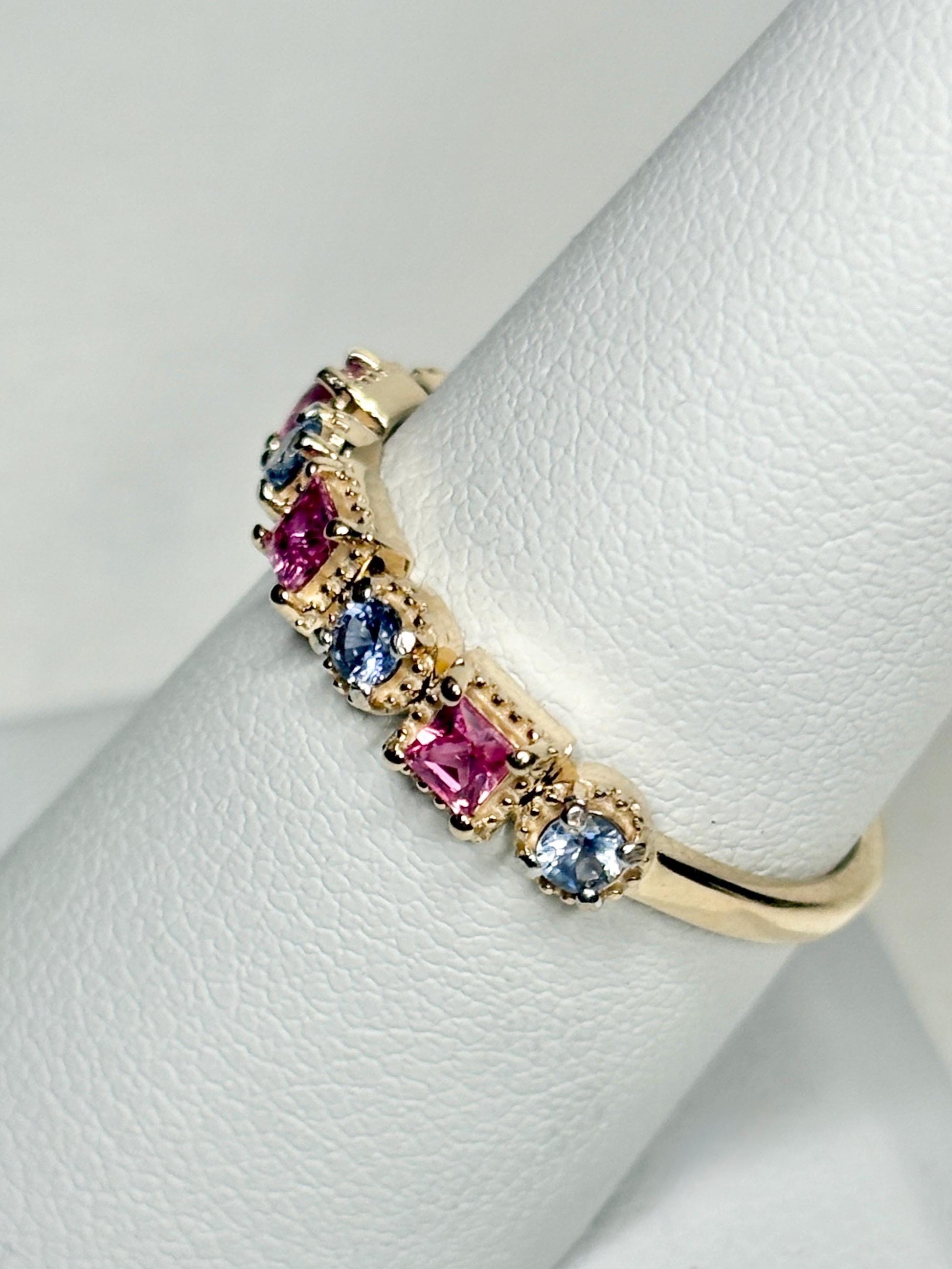 A 9k gold band ring with pink and violetish-blue sapphires.