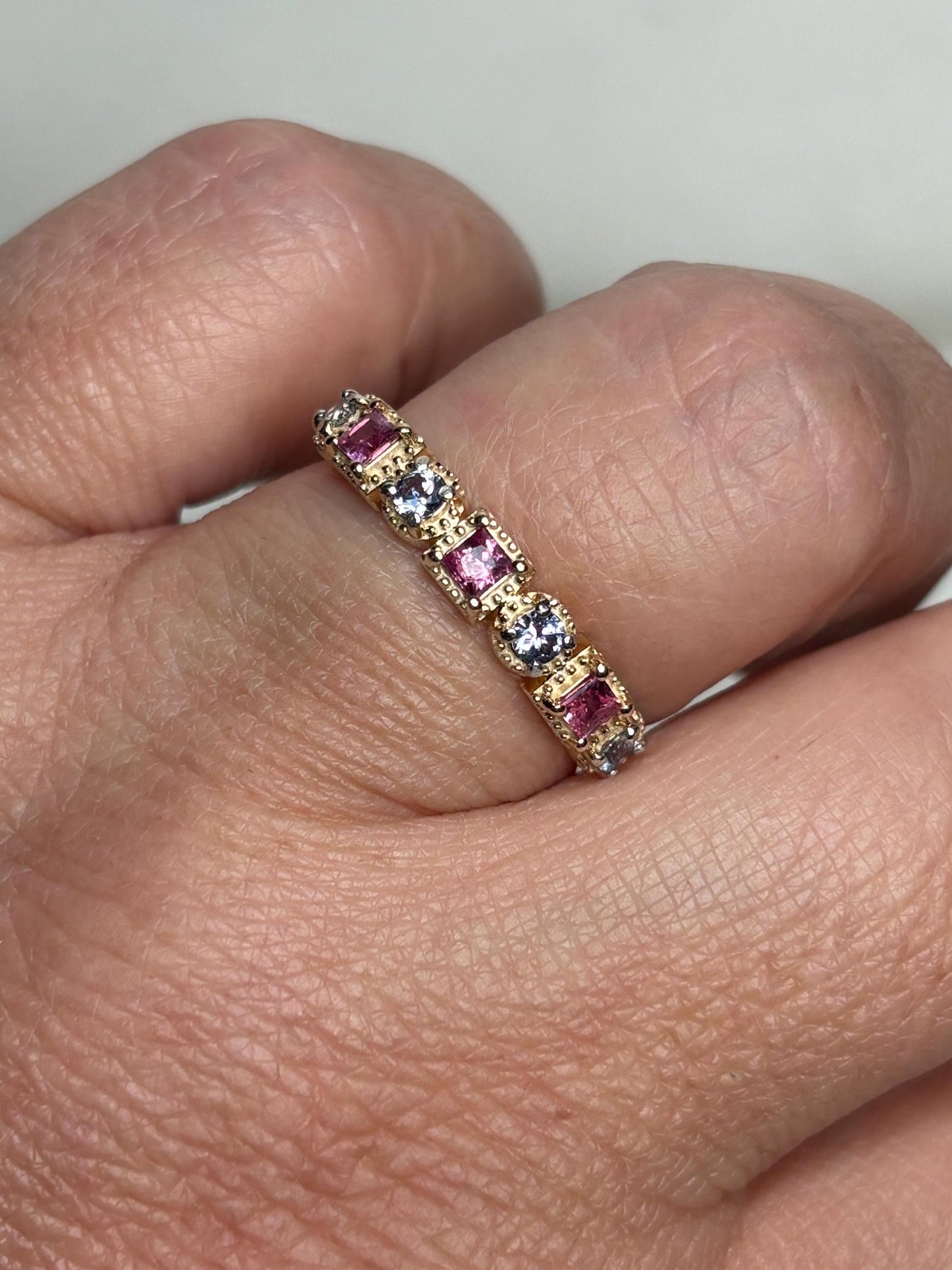 A 9k gold band ring with alternating pink and violetish-blue sapphires.