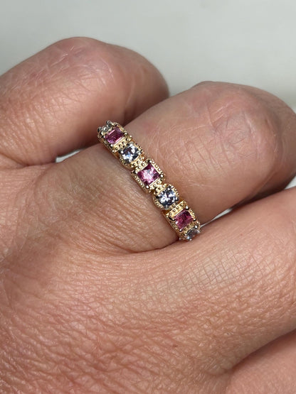 A 9k gold band ring with alternating pink and violetish-blue sapphires.