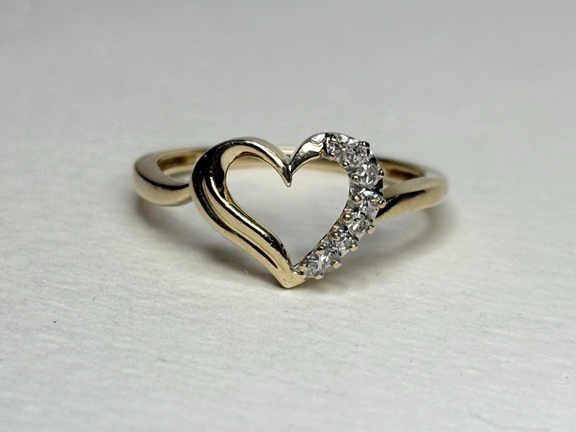A 10k yellow gold ring with a heart design featuring eight small diamonds.