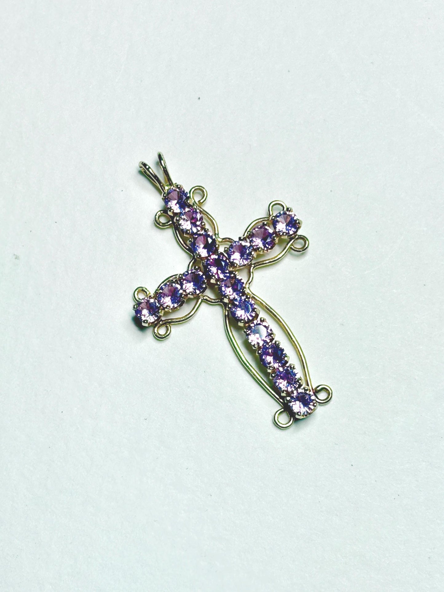 A 14k gold cross pendant with purple sapphires.