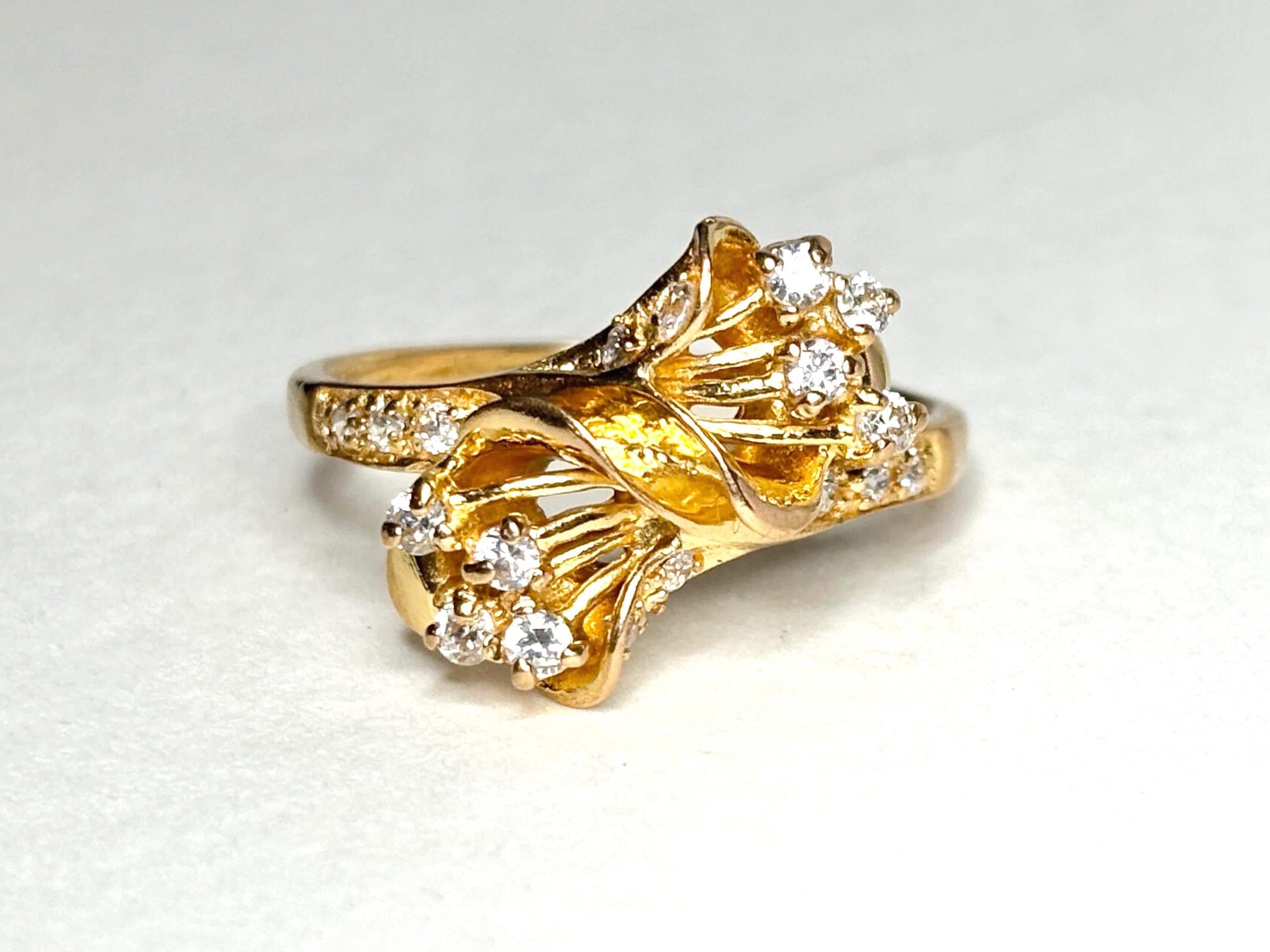 Solid 21k gold bypass ring with white stones.